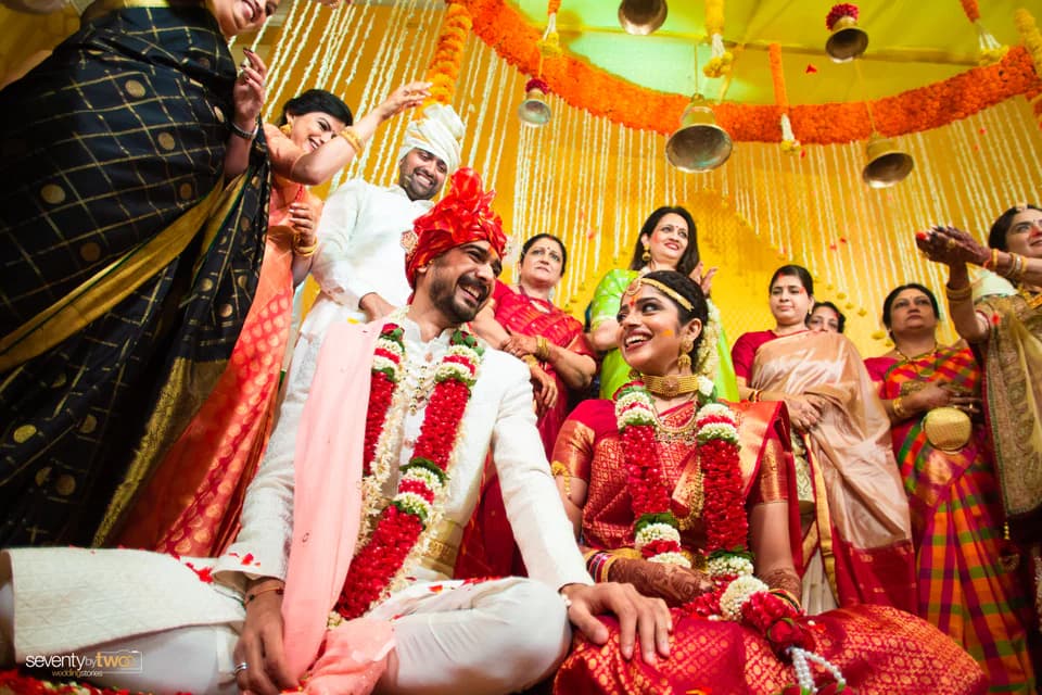 Karan and Madhavi laughing with family during a colourful Goa wedding ritual