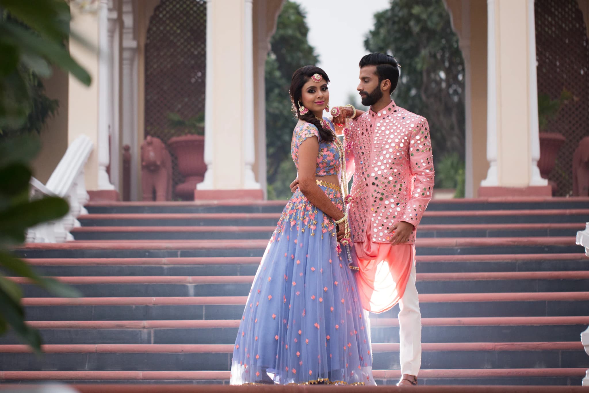 Vishal and Khushboo in colourful mehendi outfits on palace steps in Jaipur