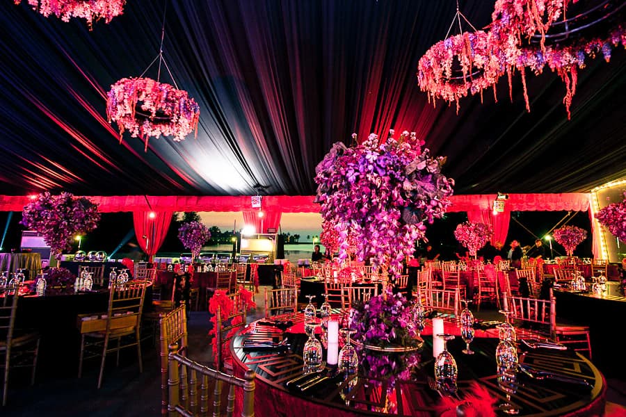 Magenta floral wedding reception with chandeliers and candlelit tables in Phuket
