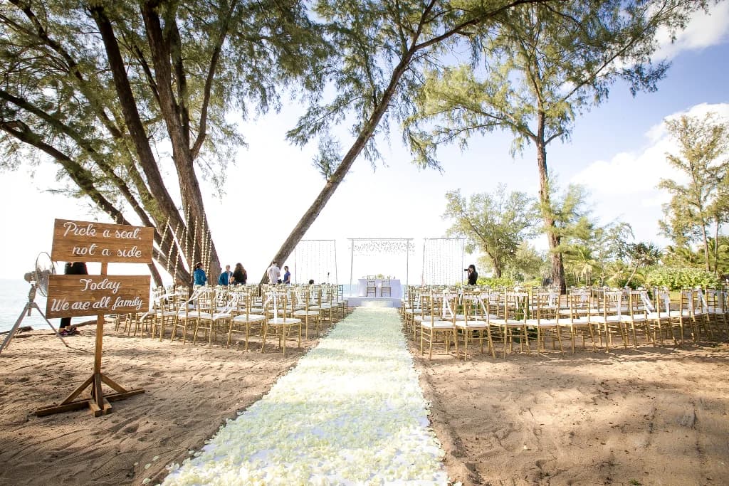 White beach wedding aisle beneath coastal trees at JW Marriott Phuket