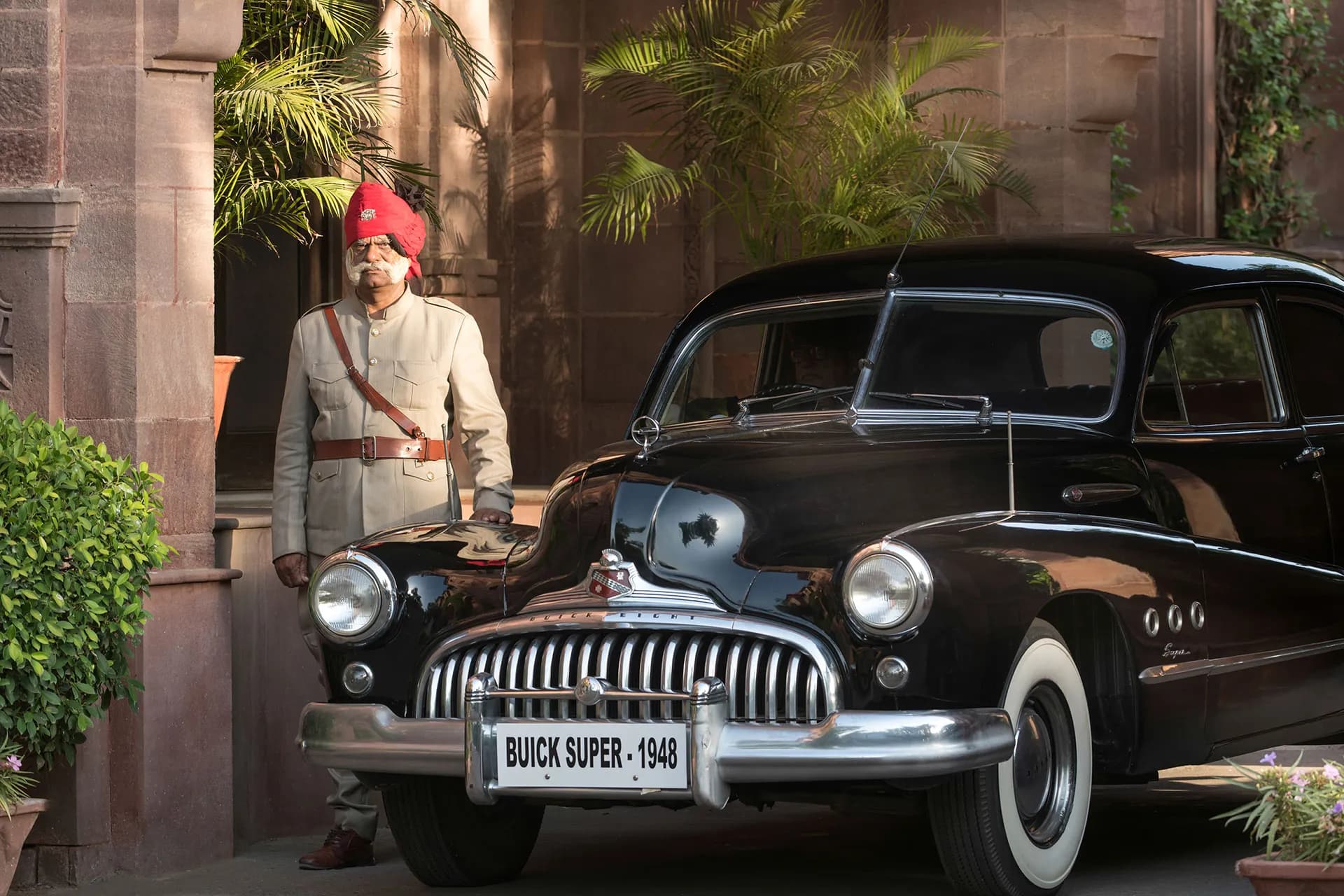 Vintage Buick and liveried Rajput attendant at the arrival porch of Ajit Bhawan Palace Jodhpur