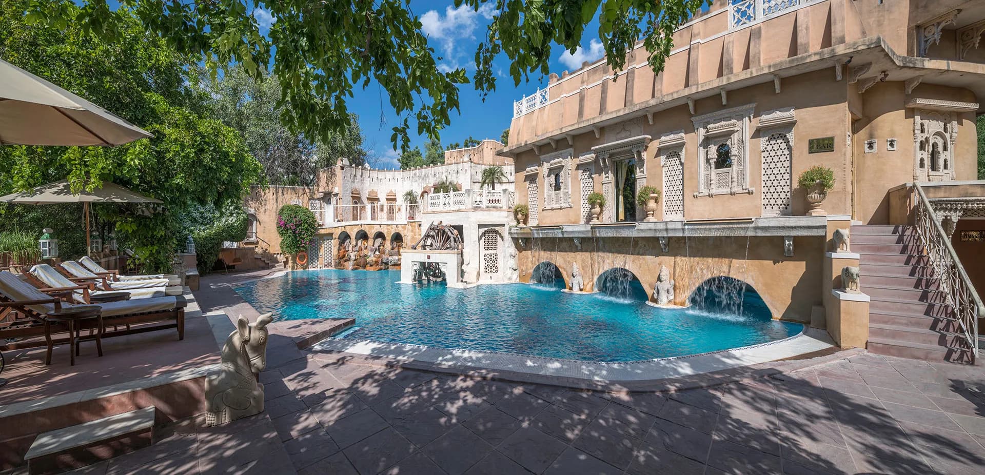 Swimming pool framed by carved sandstone palace facades at Ajit Bhawan Palace Jodhpur