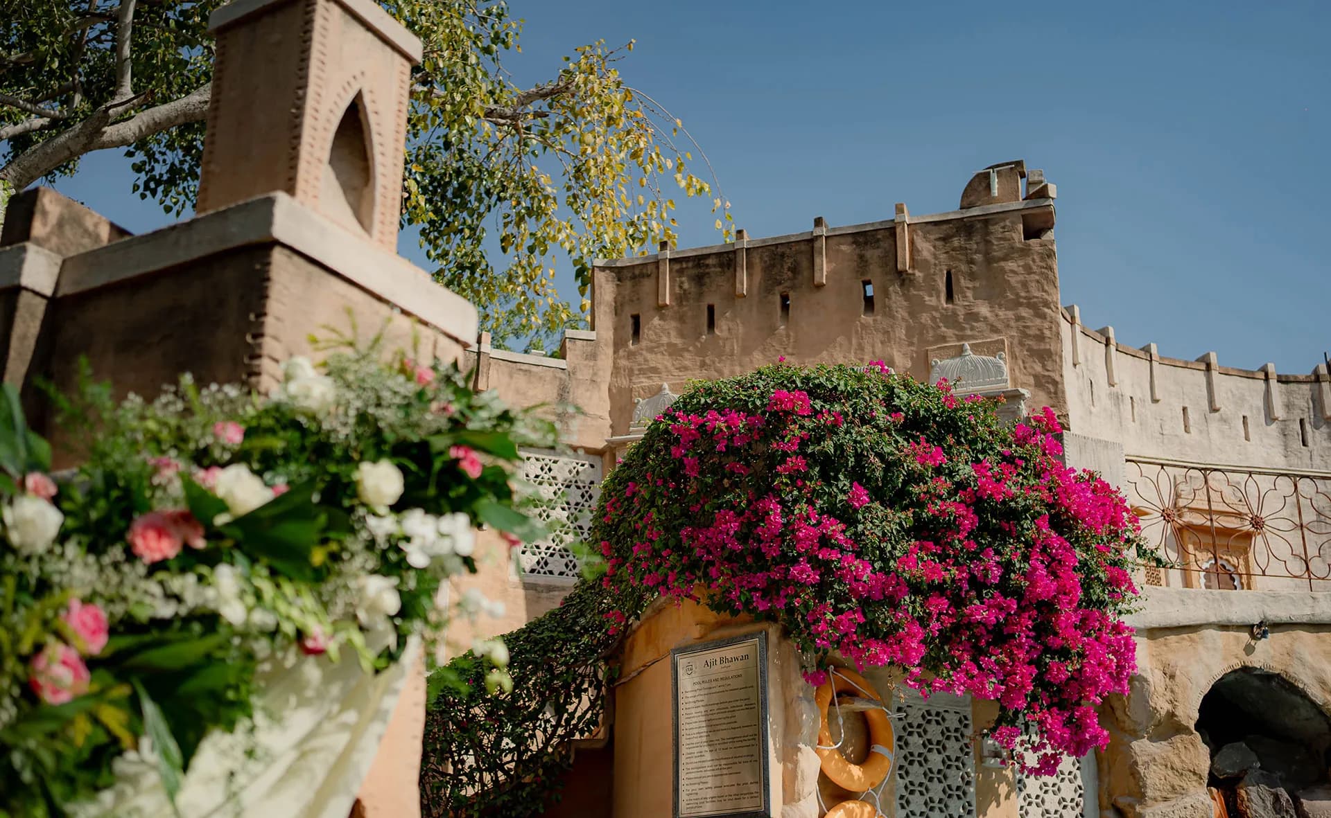 Fort-style sandstone courtyard dressed with bougainvillea and florals for a ceremony at Ajit Bhawan Palace Jodhpur