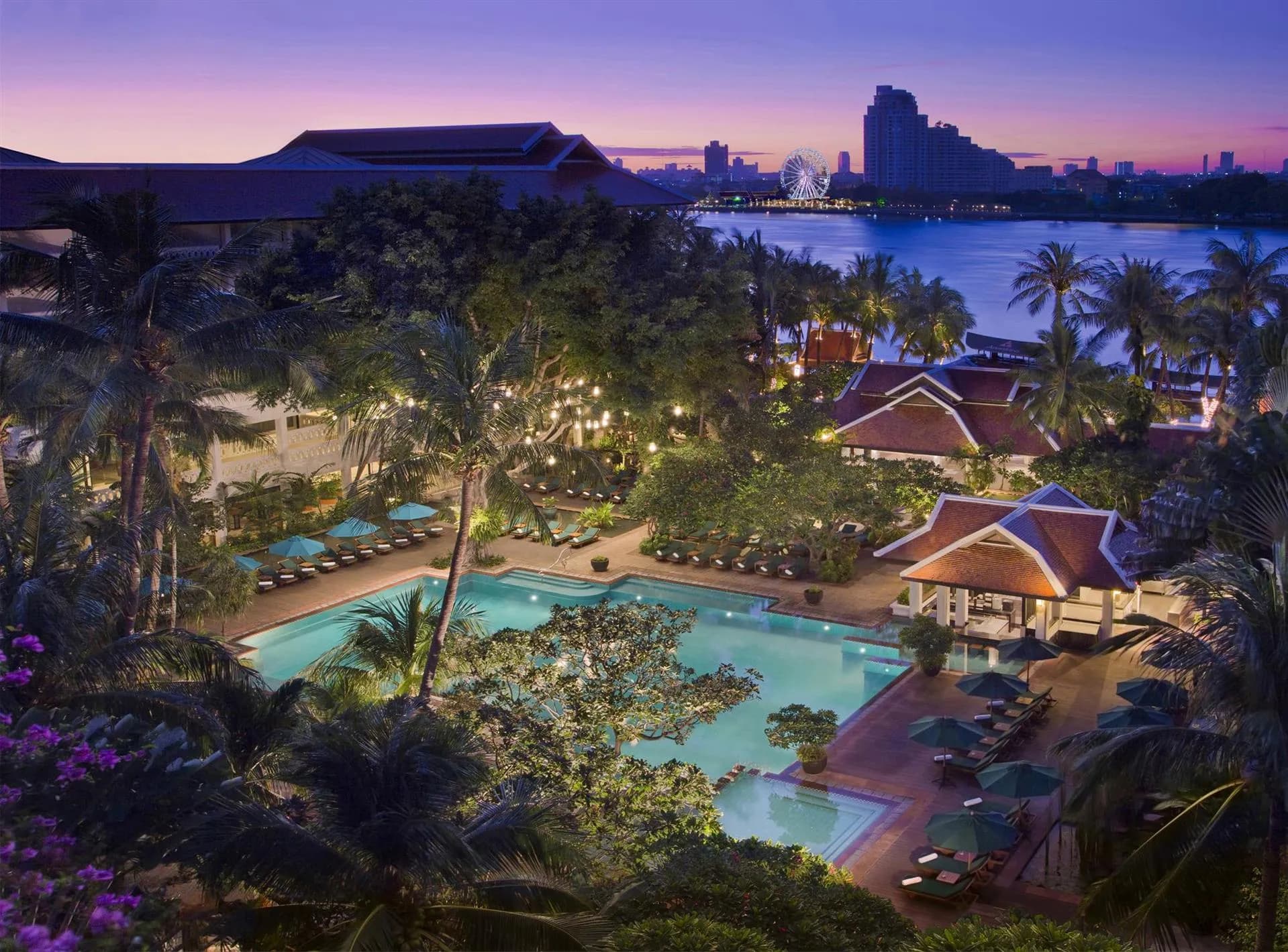 Twilight view of the riverside pool and tropical gardens at the AVANI Riverside complex on the Chao Phraya, Bangkok