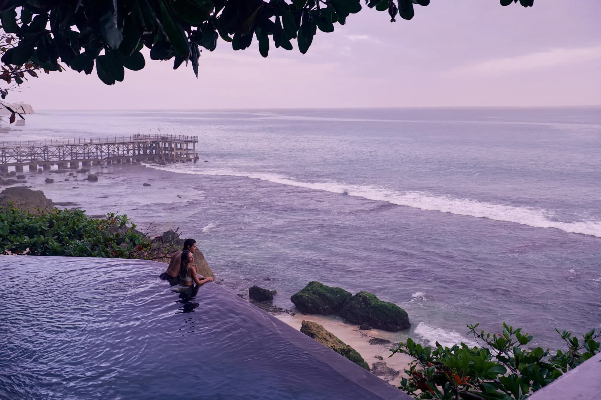 Cliff-edge infinity pool overlooking the Indian Ocean and a distant pier at AYANA Estate Bali, Jimbaran