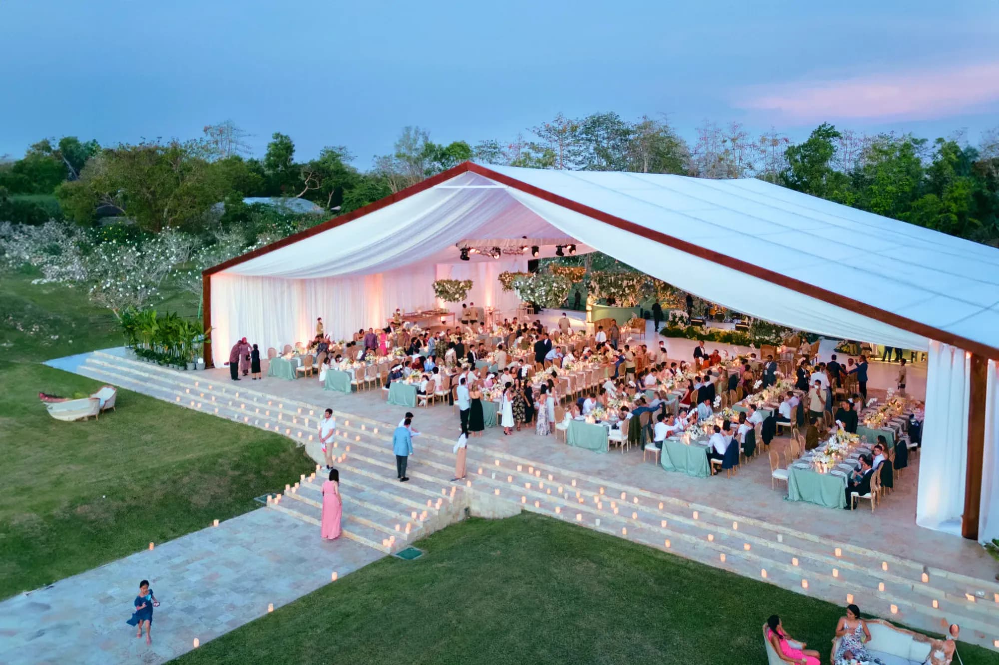 Large open-air reception with guests in Champa Garden at dusk at AYANA Estate Bali, Jimbaran