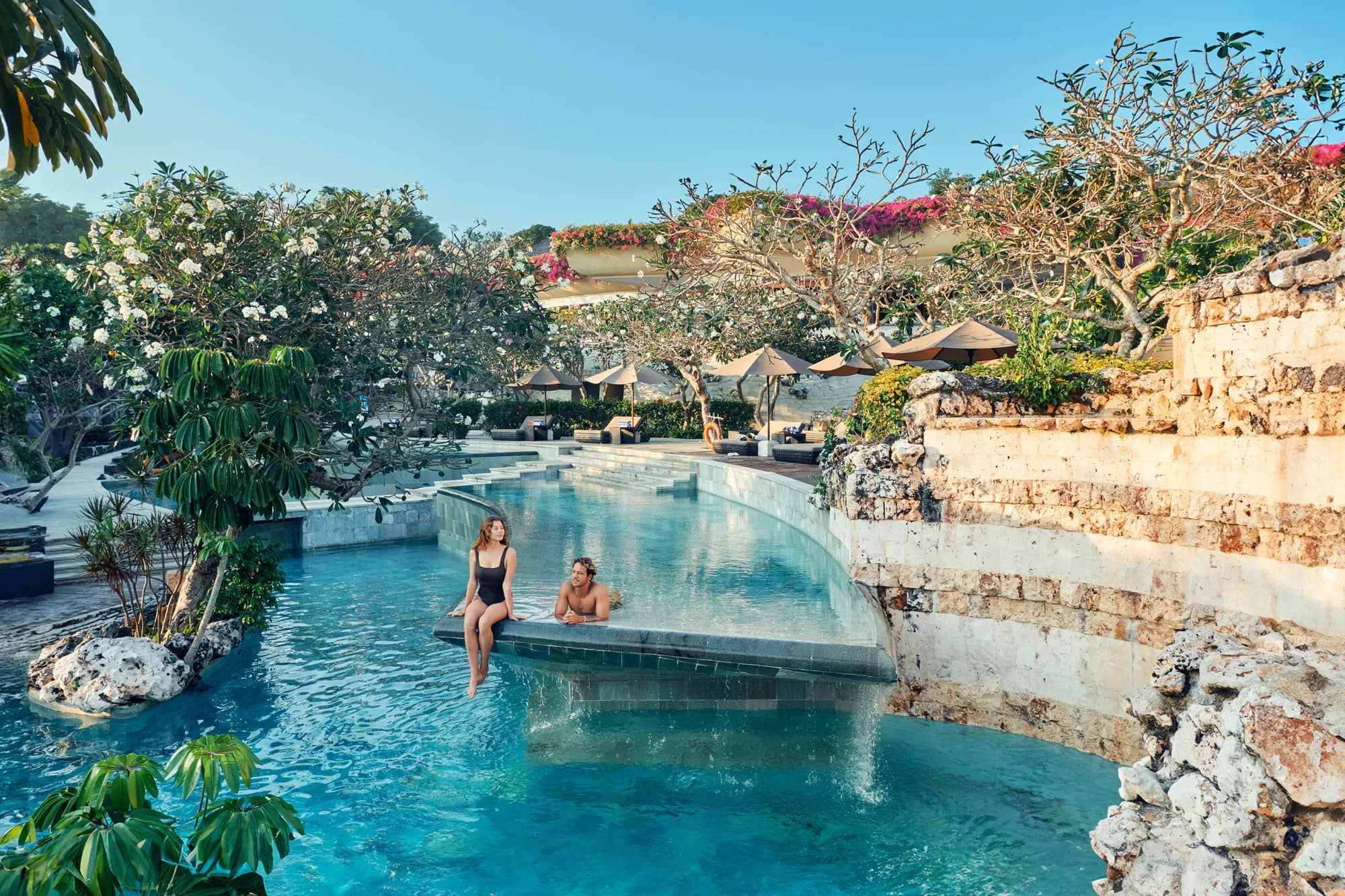 Resort swimming pool set among rock landscaping and lush greenery at AYANA Estate Bali, Jimbaran
