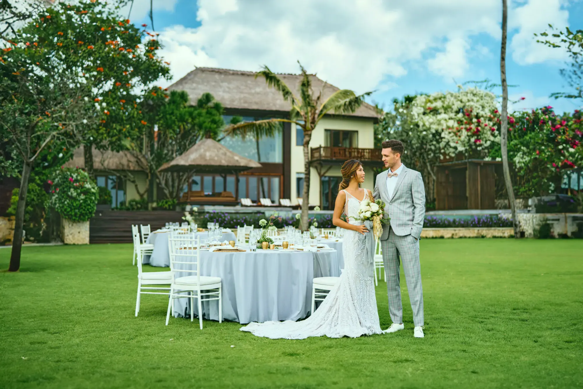 Round reception tables set on a clifftop villa lawn with ocean view at AYANA Estate Bali, Jimbaran