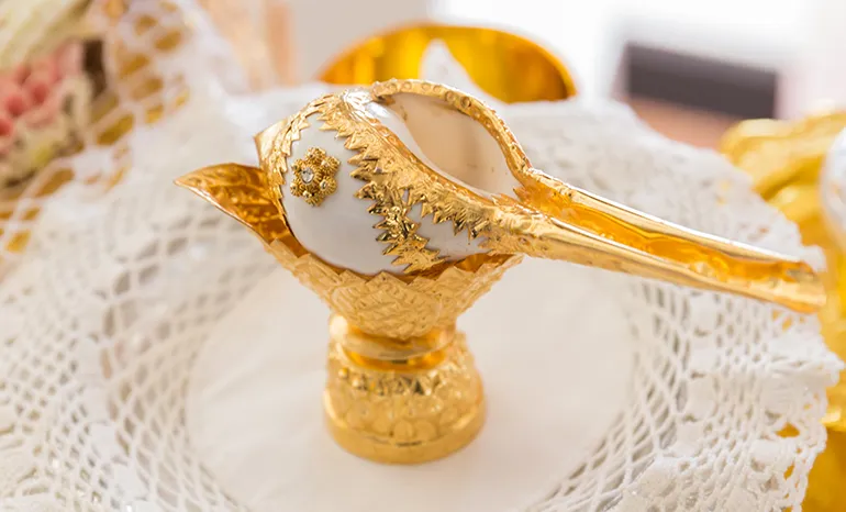 Cape Fahn Thai gold ceremonial conch water vessel detail on lace at an island wedding, Koh Samui