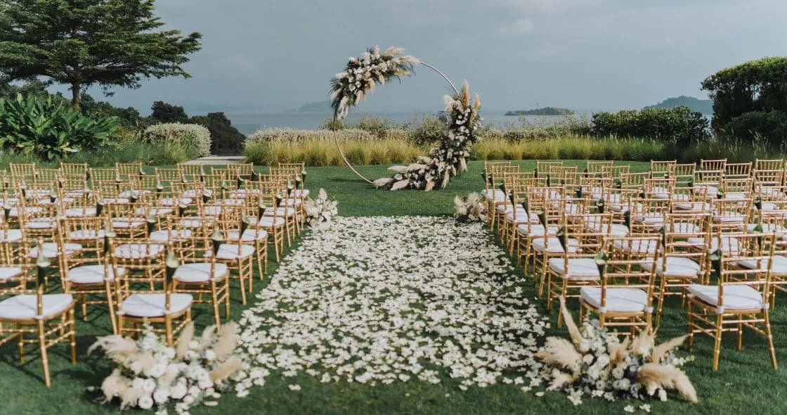 Oceanfront Lawn at COMO Point Yamu Phuket set with tables and chairs for a wedding ceremony over the bay