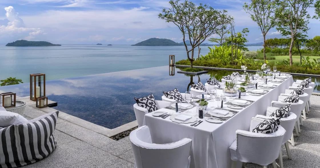Long table dinner setting on the lawn overlooking the water at COMO Point Yamu Phuket