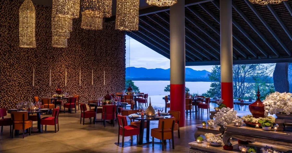 Bay-facing patio with tables and chairs set for an evening sangeet at COMO Point Yamu Phuket