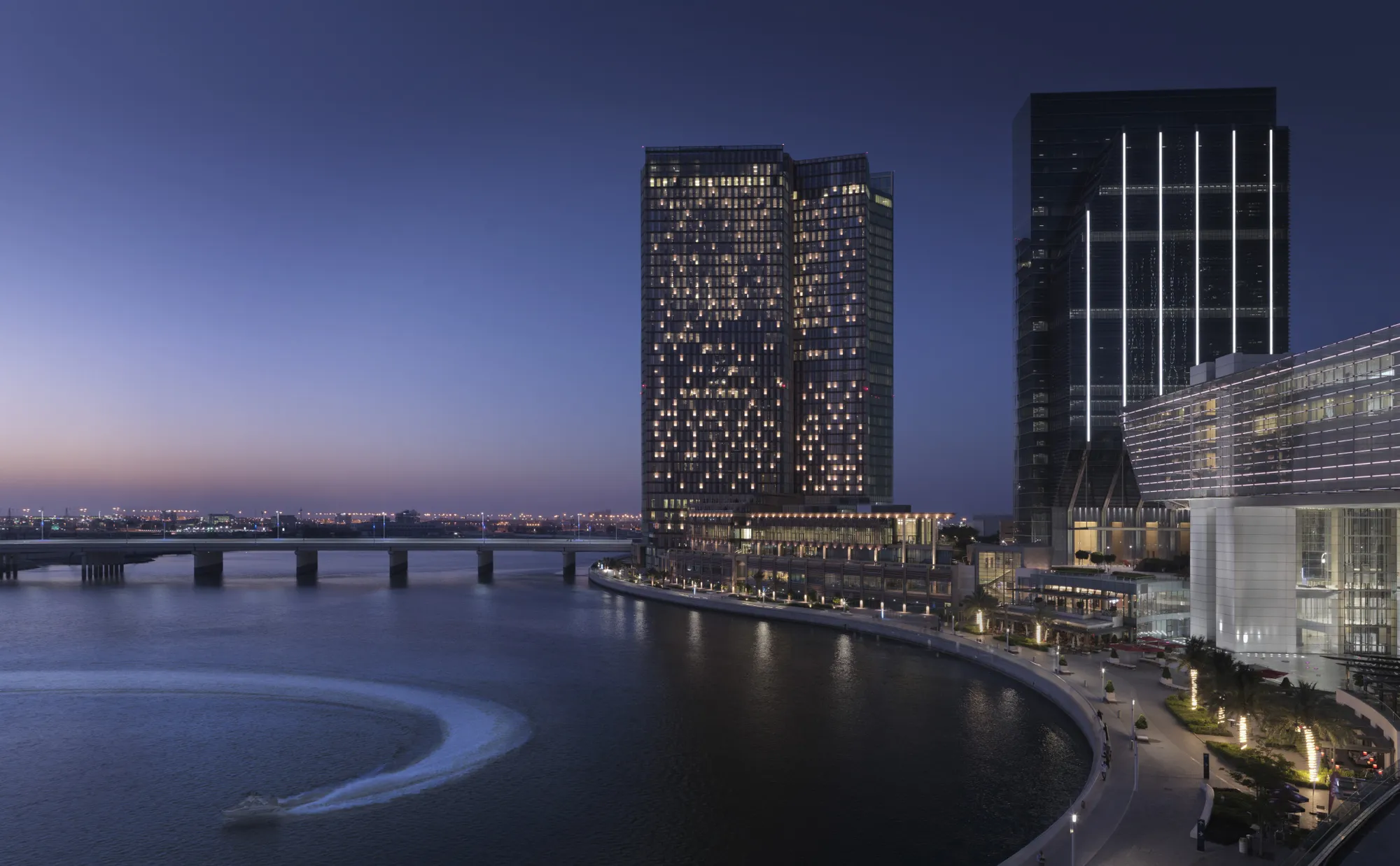 Four Seasons Hotel Abu Dhabi at Al Maryah Island twin towers lit at dusk above the Arabian Gulf waterfront and promenade