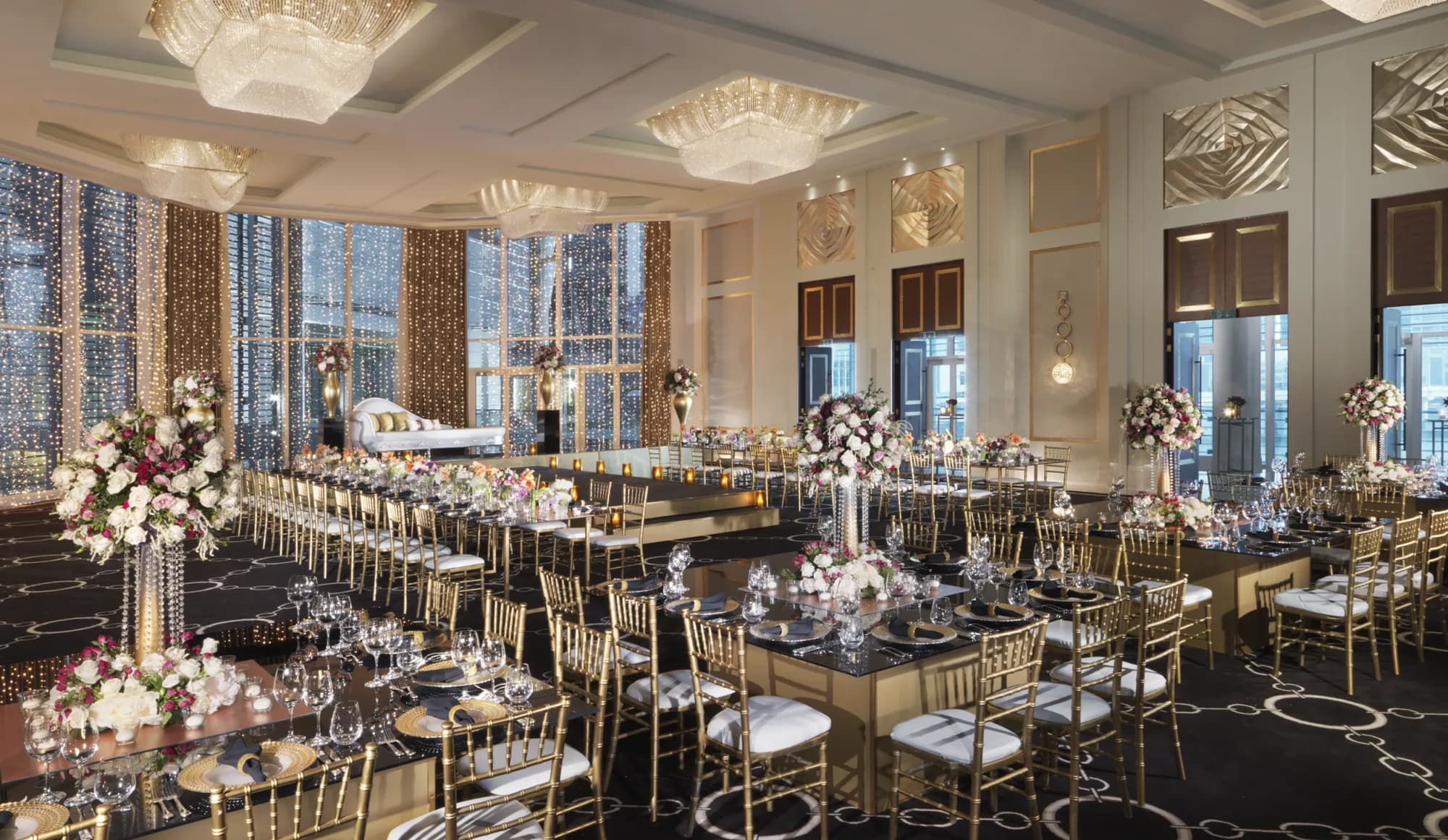 Al Maryah Ballroom at Four Seasons Abu Dhabi set with long gold banqueting tables and floral centrepieces