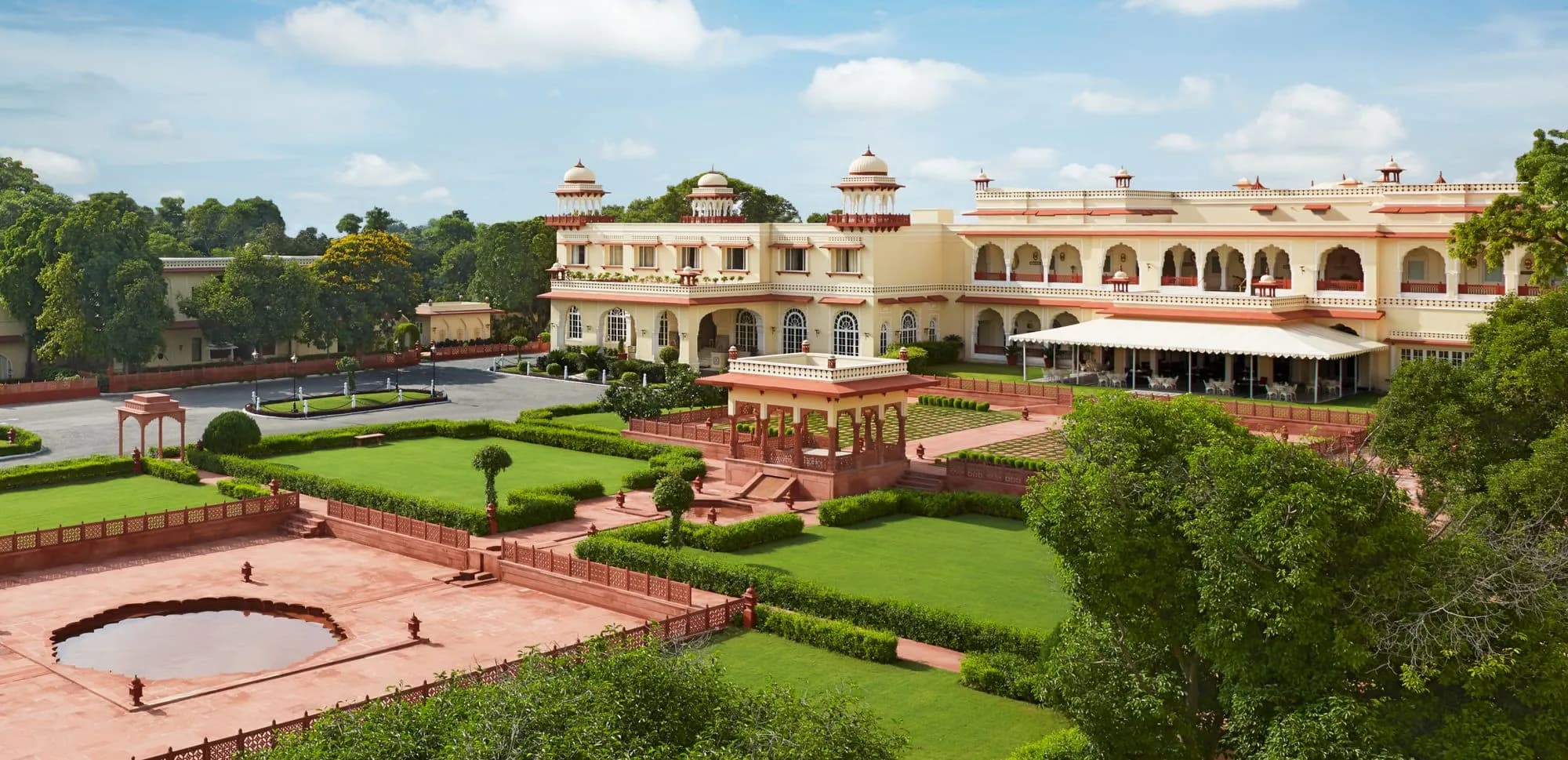 Jai Mahal Palace Jaipur Indo-Saracenic palace facade lit at dusk above landscaped Mughal gardens