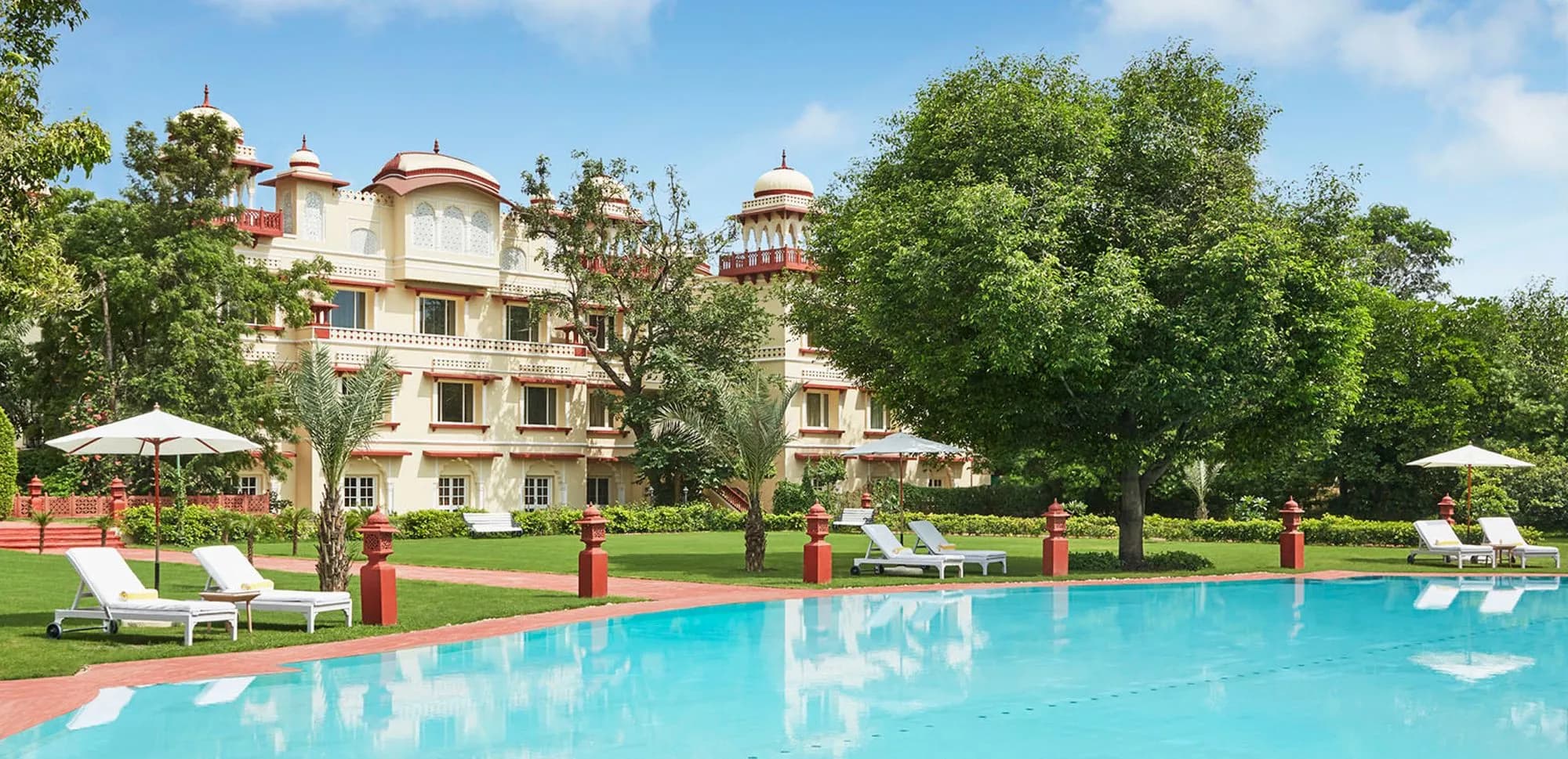 Poolside lawn with illuminated fountain and garden paths at Jai Mahal Palace Jaipur