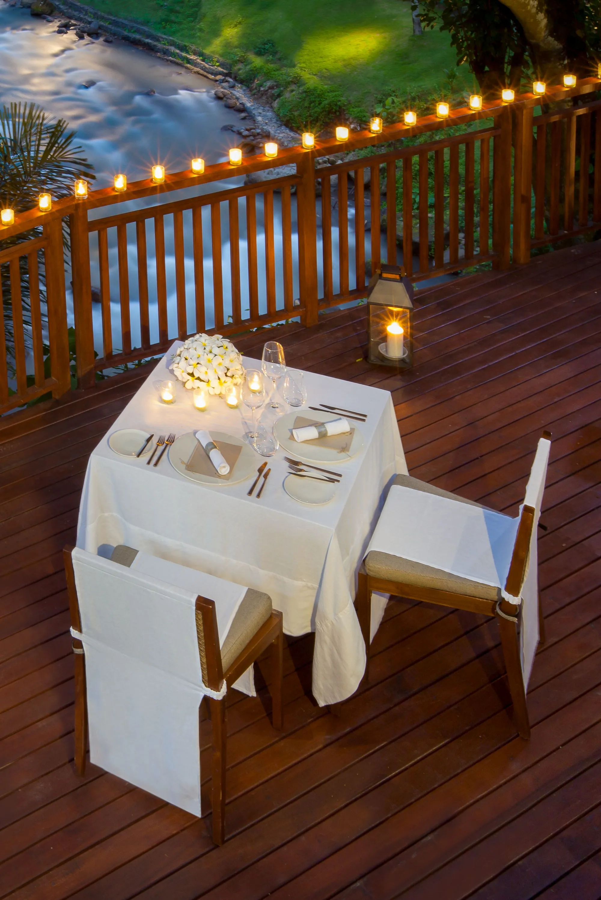 Private romantic riverside dinner setup with candles at Mandapa a Ritz-Carlton Reserve Ubud Bali