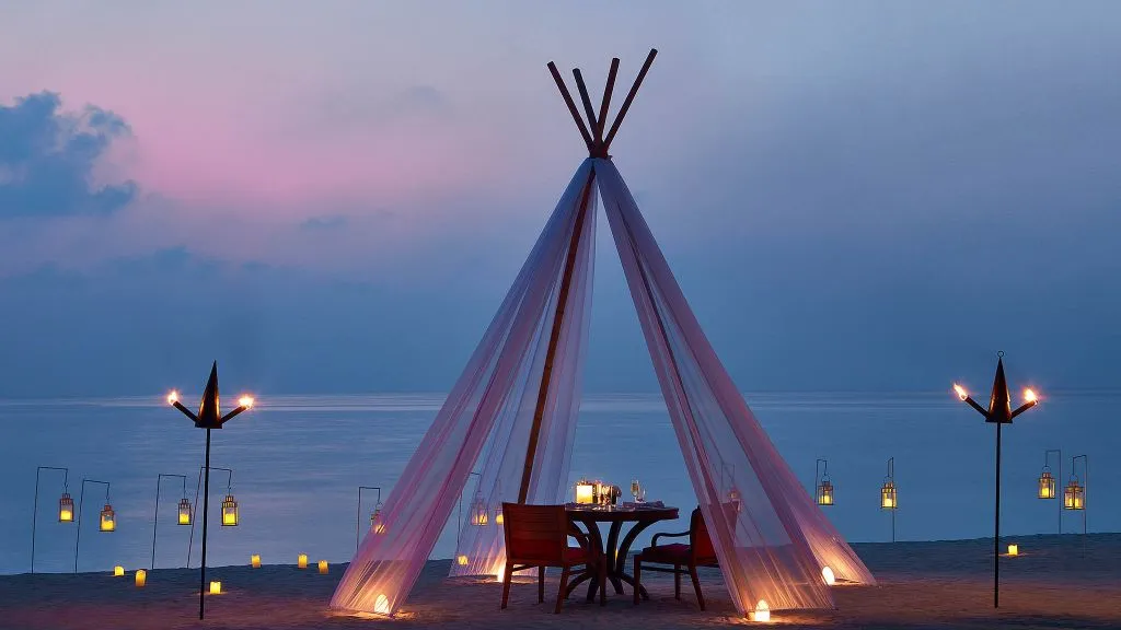 Private candlelit beach dinner setup at One&Only Reethi Rah, Maldives hospitality