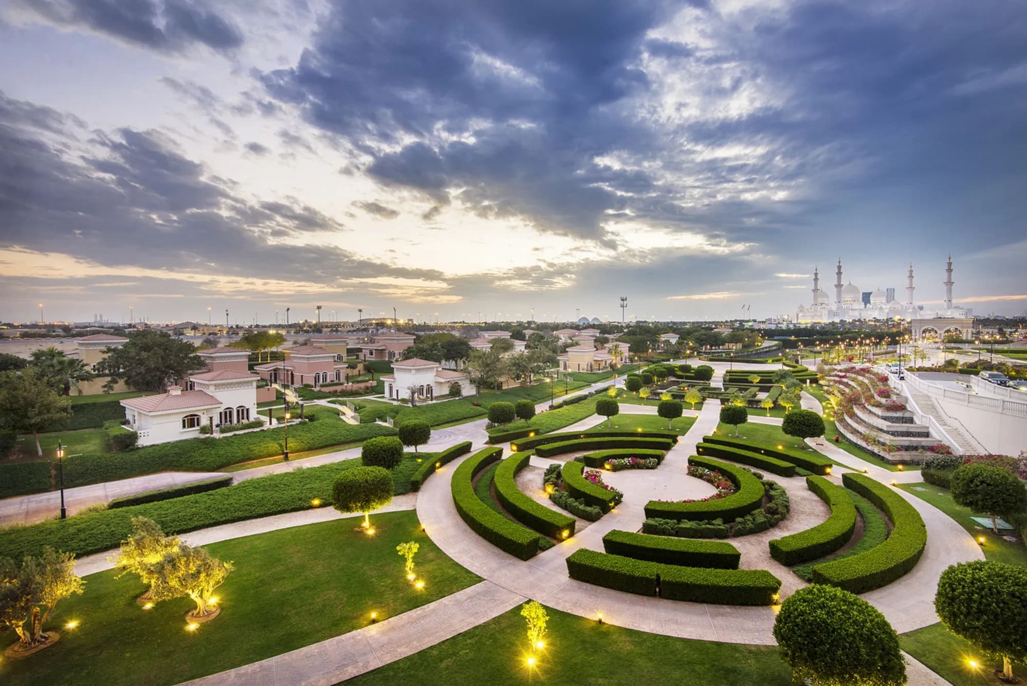 Manicured Venetian-style maze gardens at dusk with Sheikh Zayed Grand Mosque on the horizon at The Ritz-Carlton Abu Dhabi Grand Canal