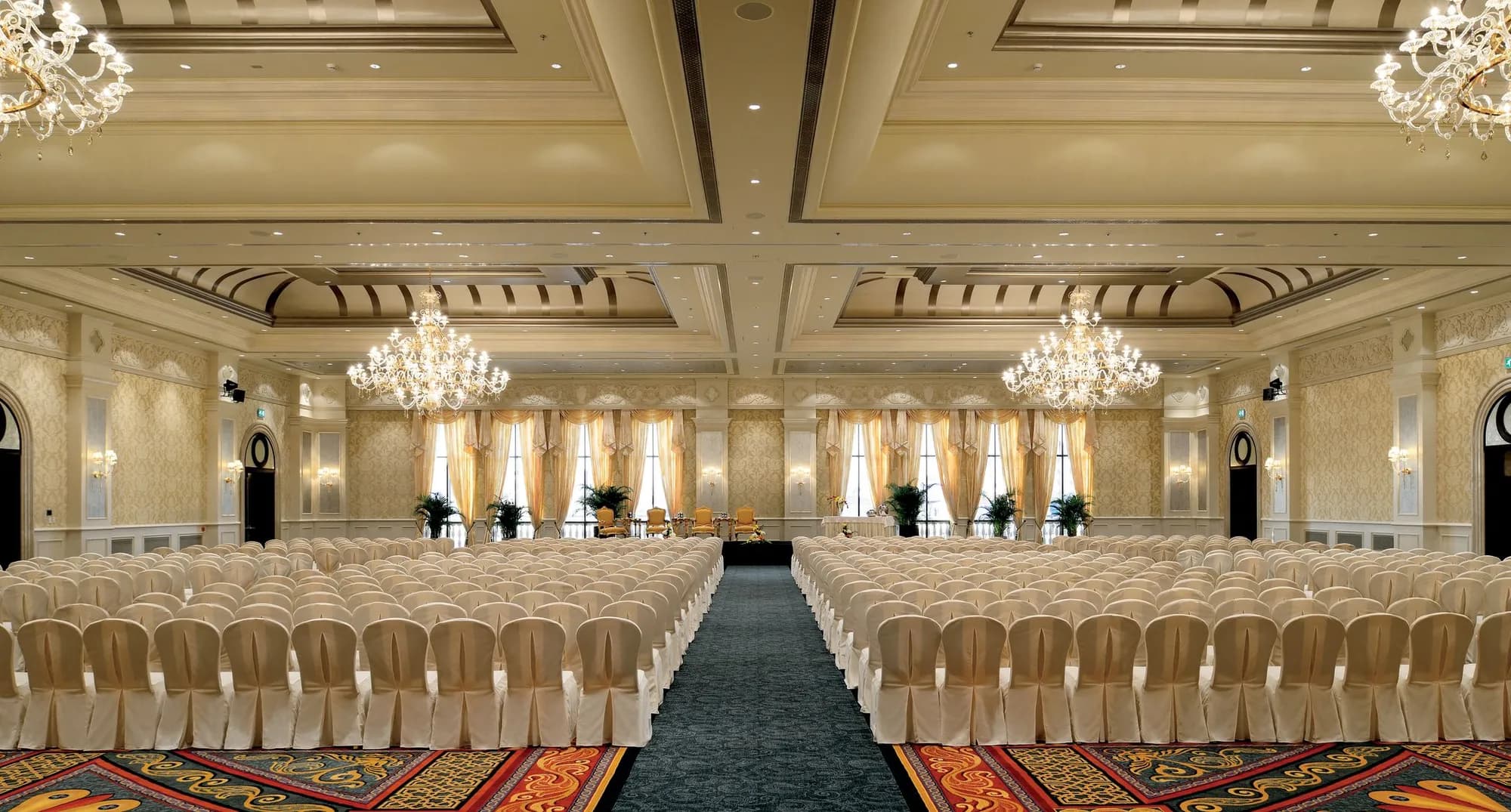 Roma Ballroom set with rows of chairs, chandeliers and draped windows at The Ritz-Carlton Abu Dhabi Grand Canal