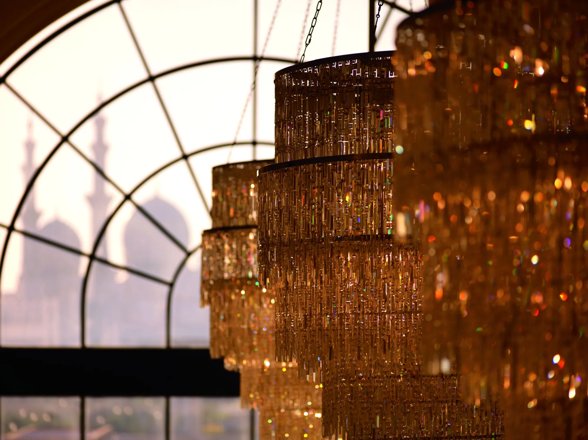 Crystal chandeliers framing the silhouette of Sheikh Zayed Grand Mosque through an arched window at The Ritz-Carlton Abu Dhabi Grand Canal
