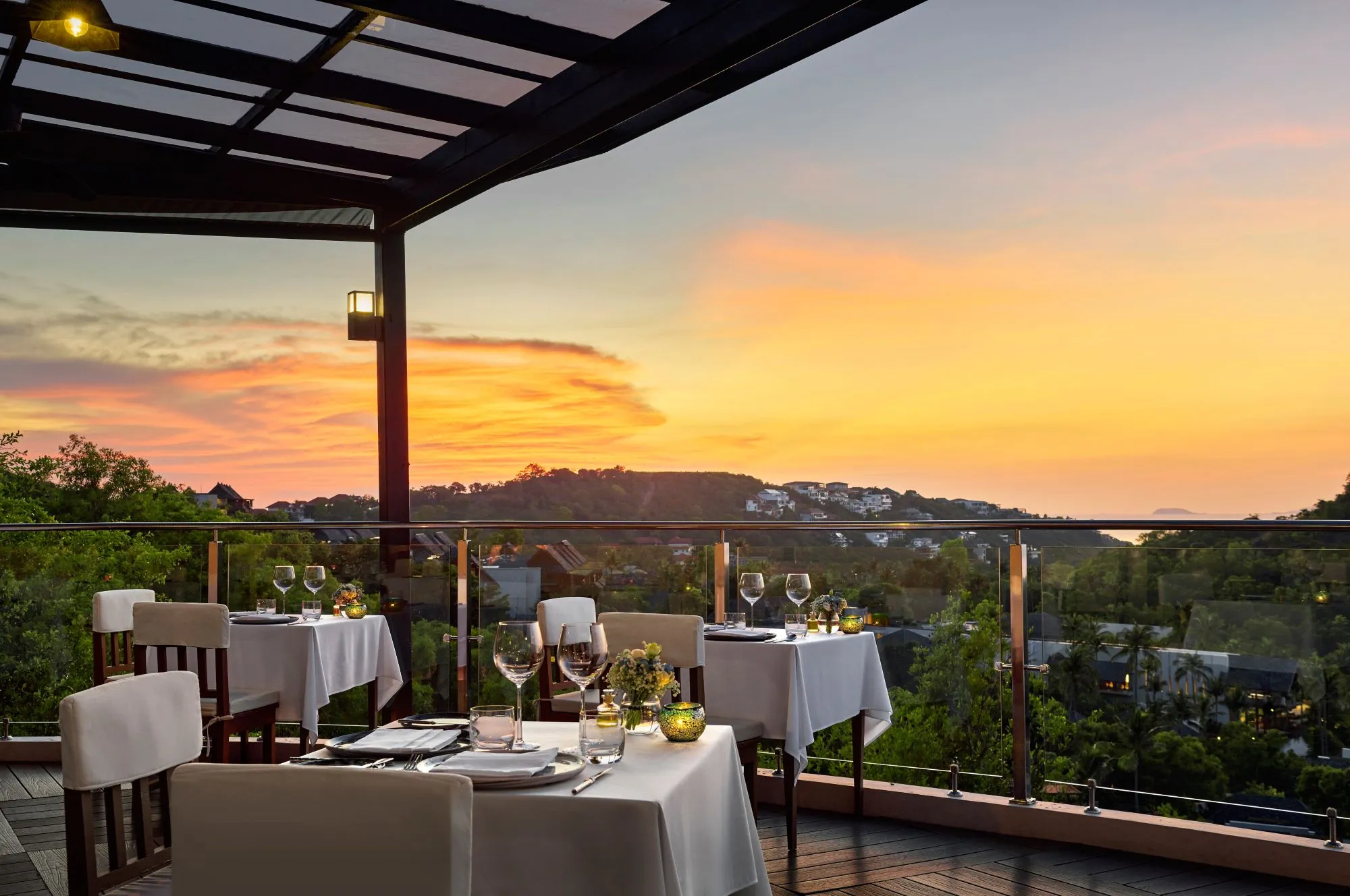 Rooftop deck restaurant set for dinner at sunset over Koh Samui at The Ritz-Carlton Koh Samui