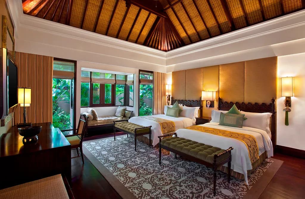 St. Regis Lagoon Villa bedroom with carved headboards and a thatched Balinese roof at The St. Regis Bali Resort, Nusa Dua