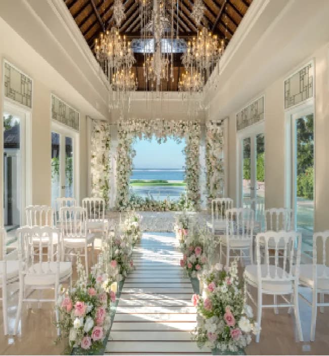 White-and-pink floral arch and petal-lined aisle inside the glass Cloud Nine Chapel at The St. Regis Bali Resort, Bali