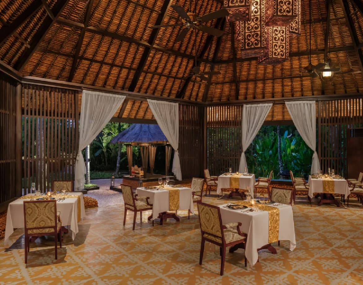Thatched Balinese-pavilion restaurant with traditional decor set for dining at The St. Regis Bali Resort, Nusa Dua