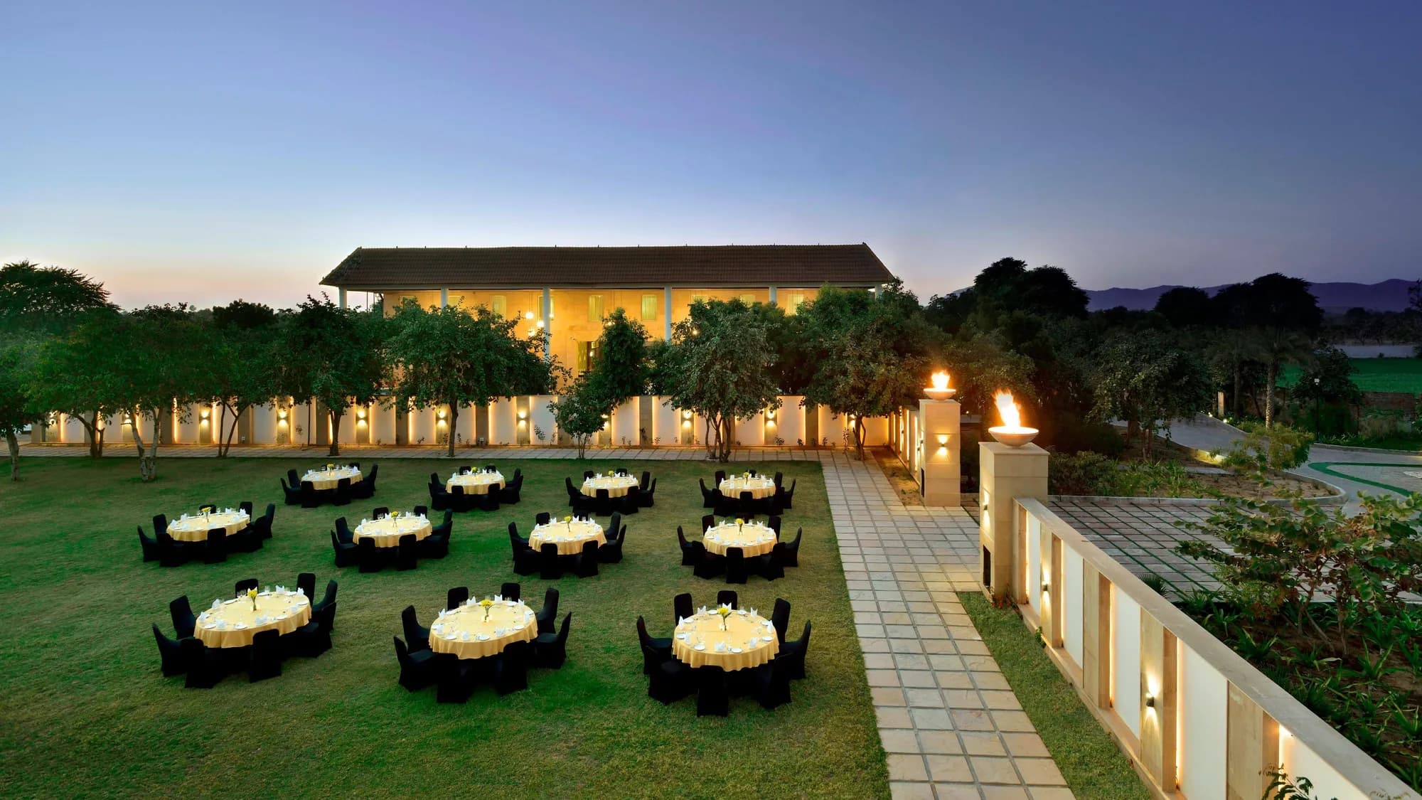 Wide manicured wedding lawn framed by palms and the Aravalli hills at The Westin Pushkar Resort & Spa