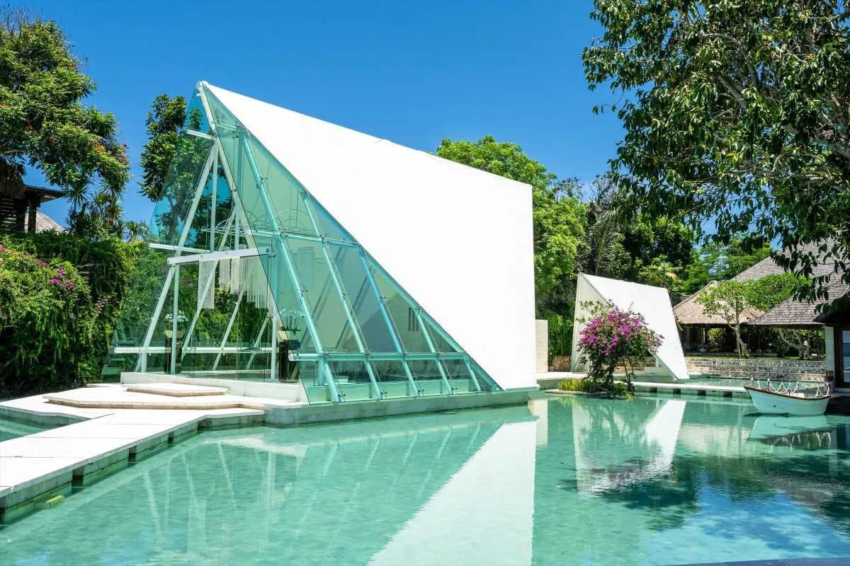 Iconic glass wedding chapel ceremony framed by the Indian Ocean at Tirtha Uluwatu, Bali