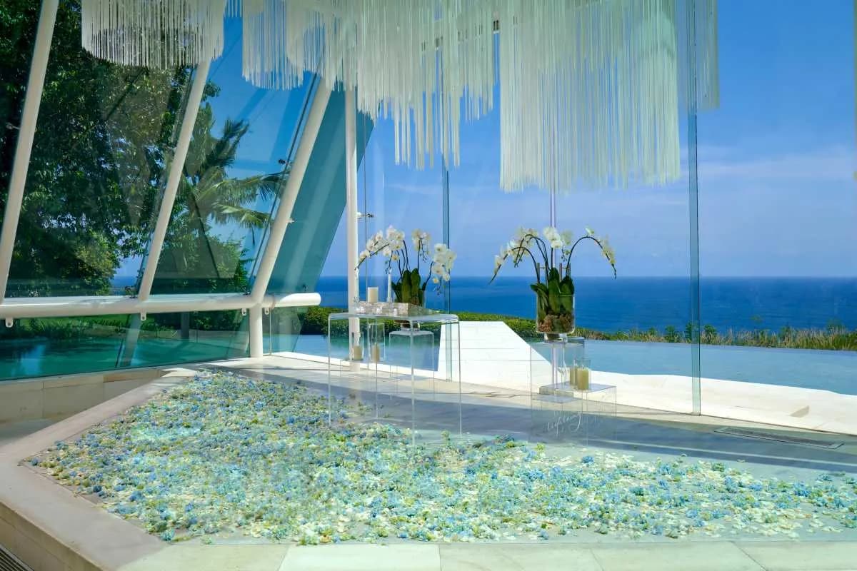 Glass chapel interior with natural light and Indian Ocean view at Tirtha Uluwatu, Bali