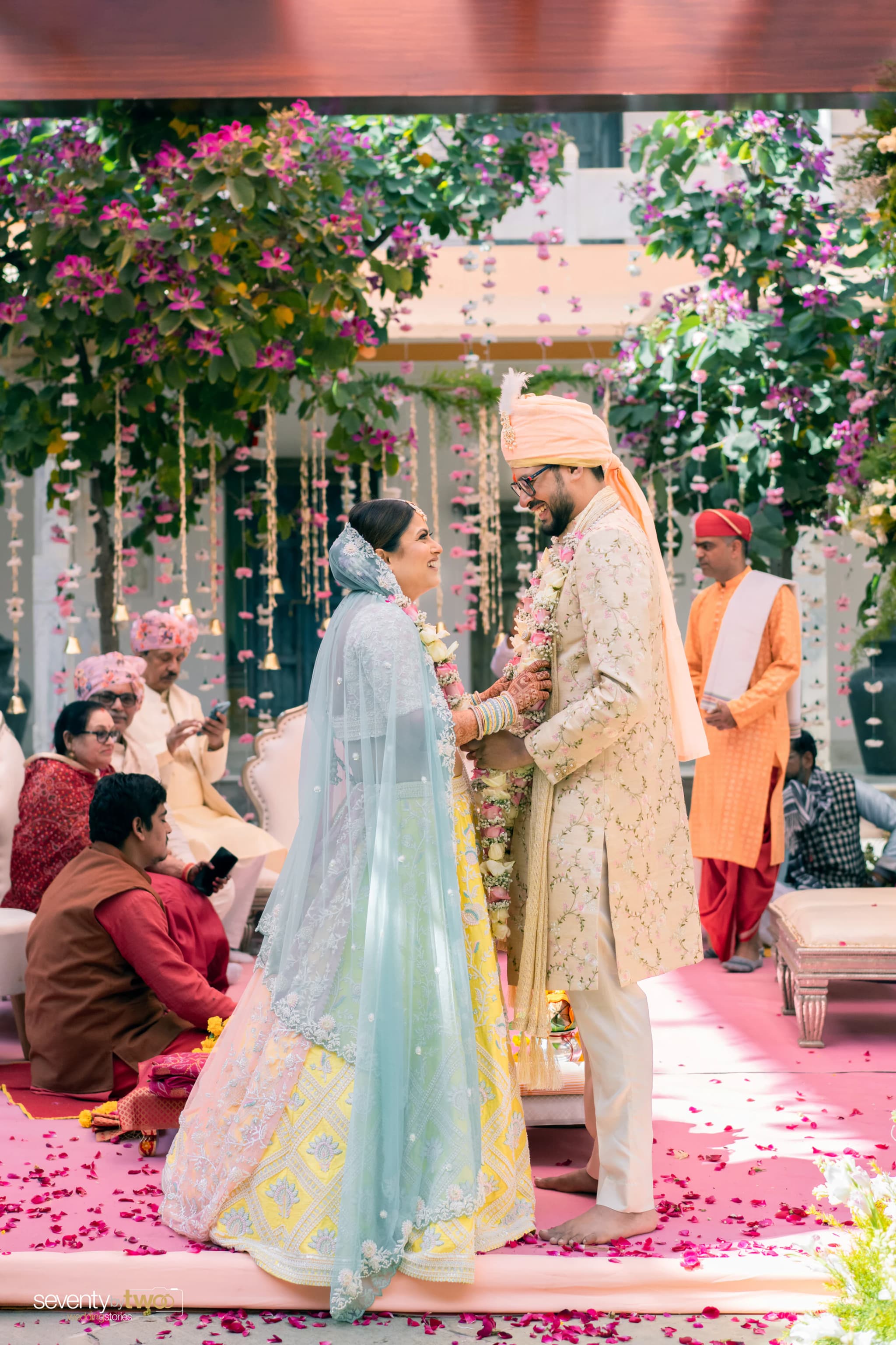 Anirudha and Shruti standing together beneath hanging flowers during their wedding