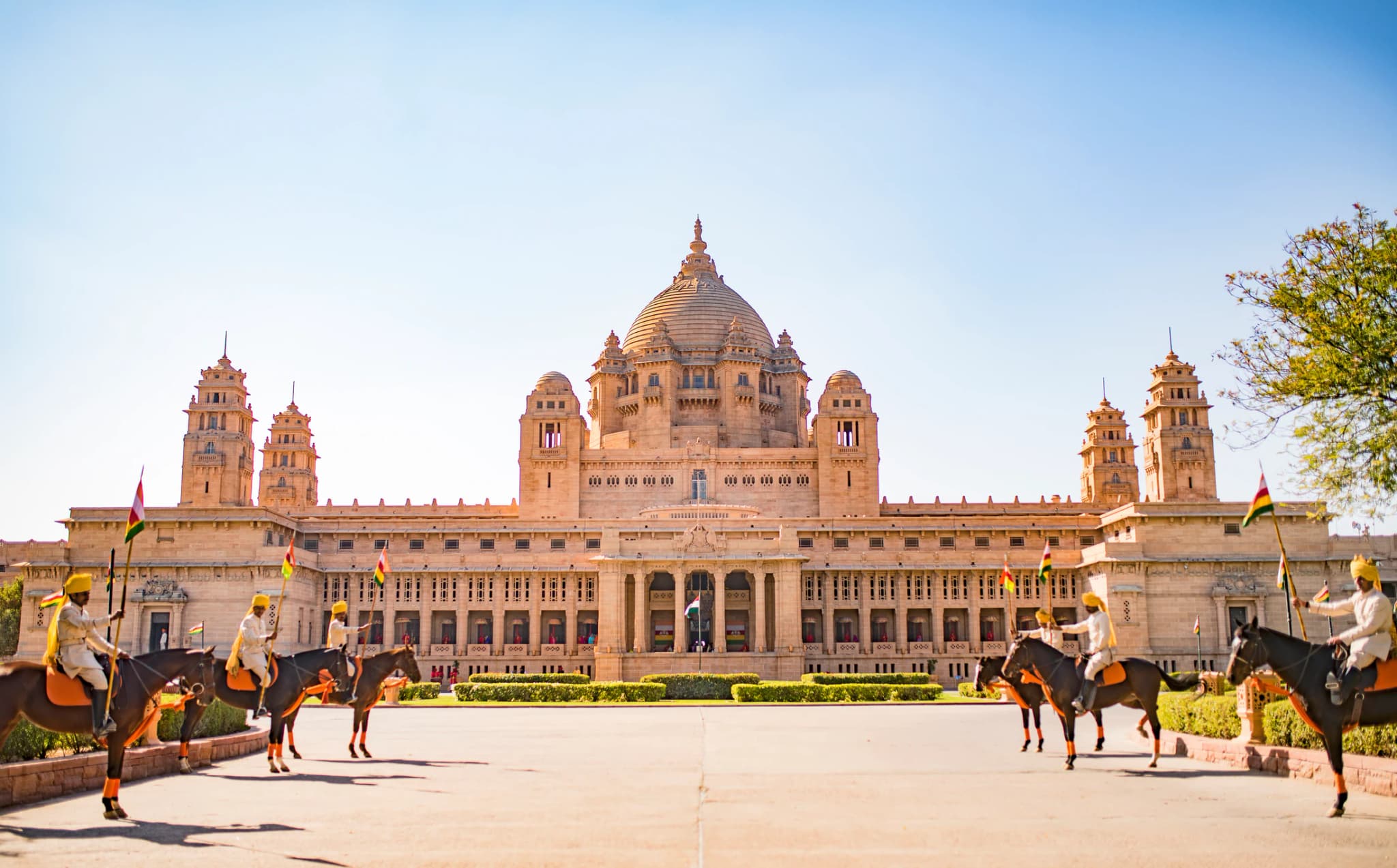 Grand sandstone palace and ceremonial horses in a wide daylight view