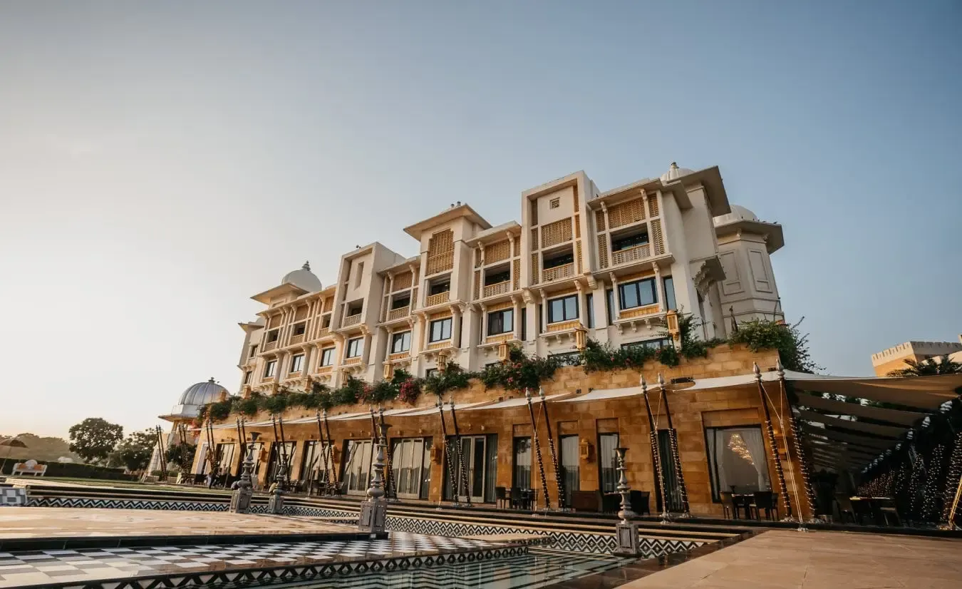 White-marble Udaipur palace exterior with reflecting pool at golden hour
