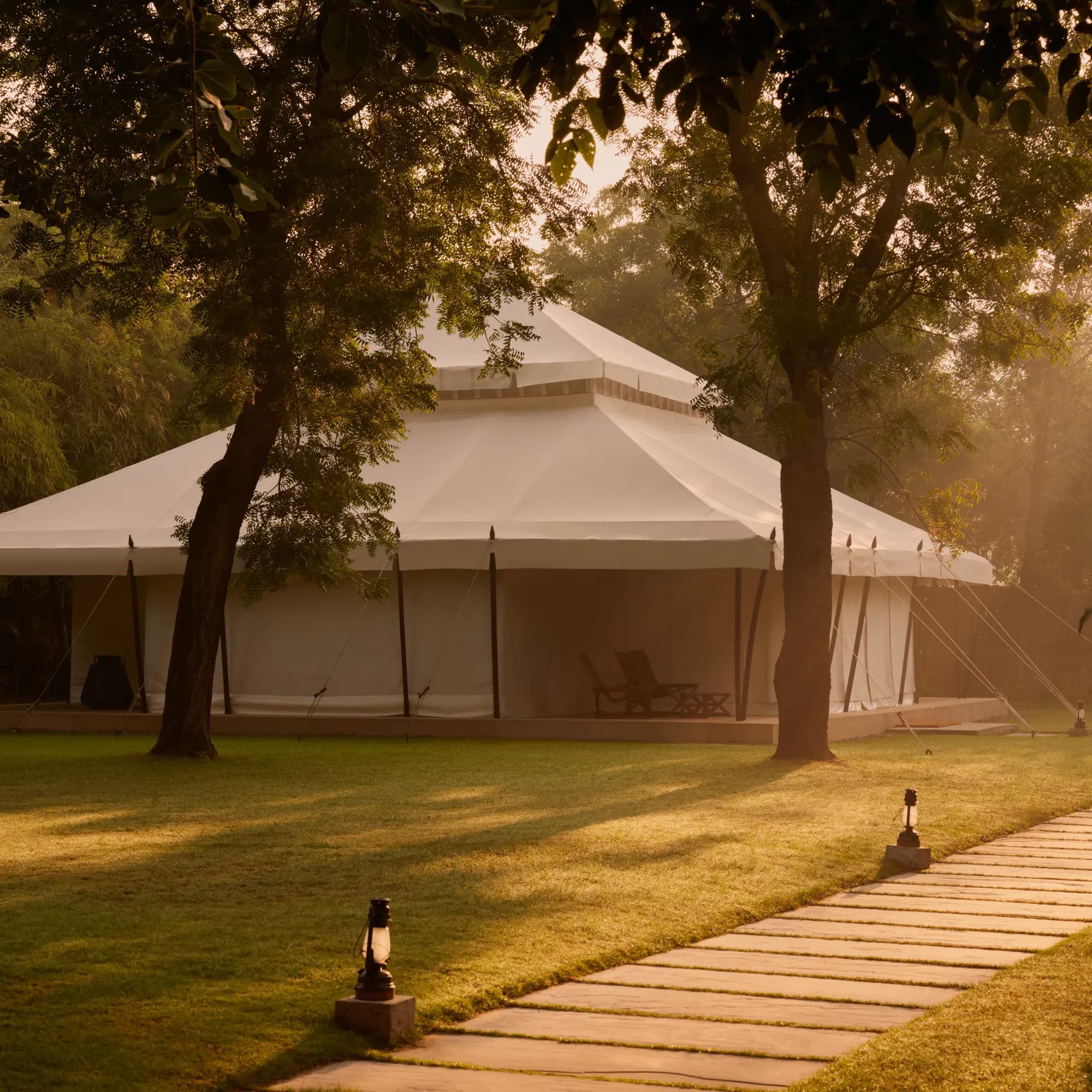 Aman-i-Khas Ranthambore soaring cream canvas Mughal-style tented pavilion lit golden at dusk among trees on the edge of Ranthambore National Park