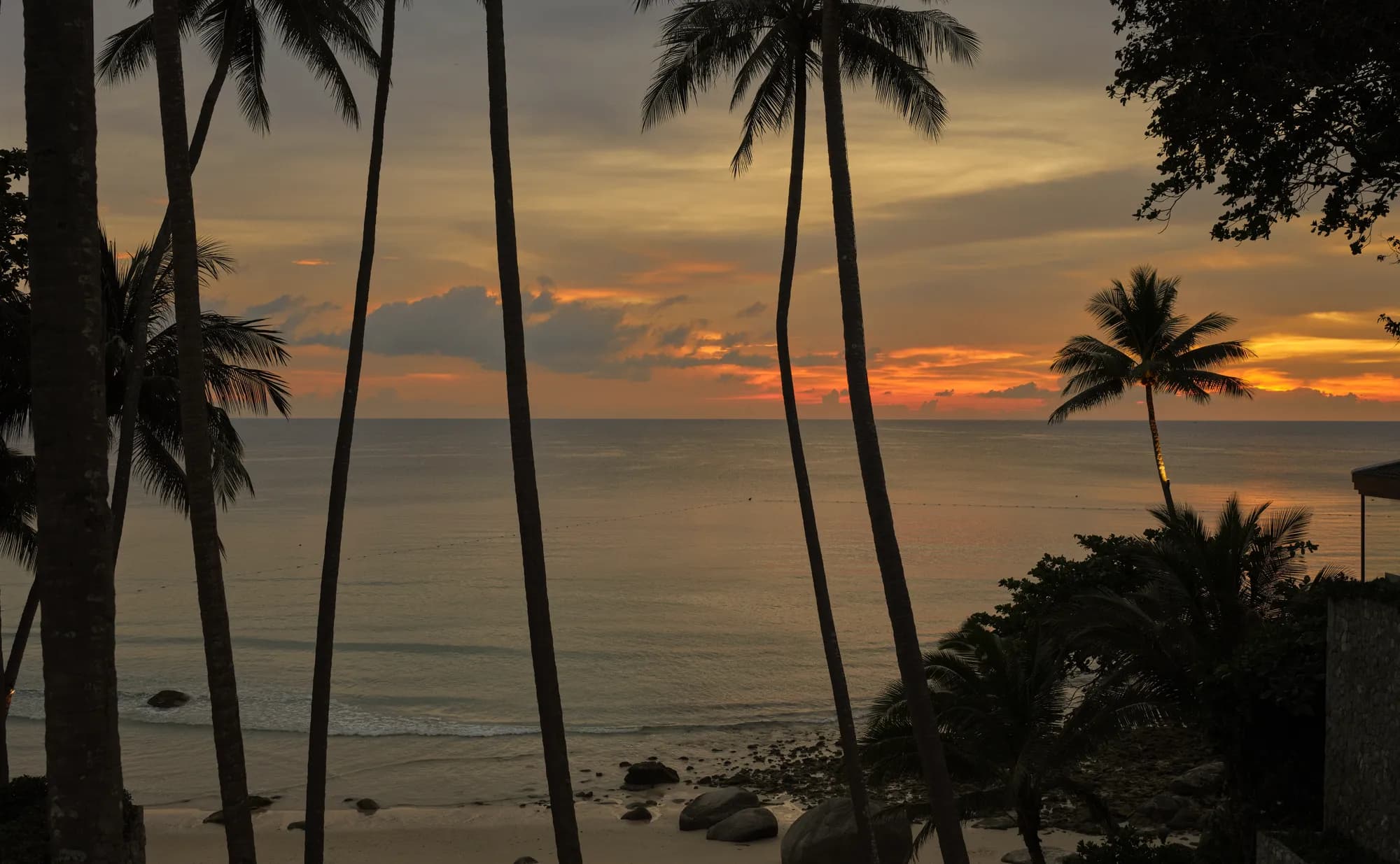 Sunset over the Andaman Sea and white-sand beach below the Amanpuri headland resort at Pansea Beach, Phuket, Thailand