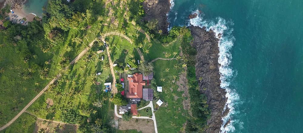 Aerial view of the Anantara Peace Haven Tangalle clifftop headland, coconut estate and rocky shoreline on Sri Lanka's south coast