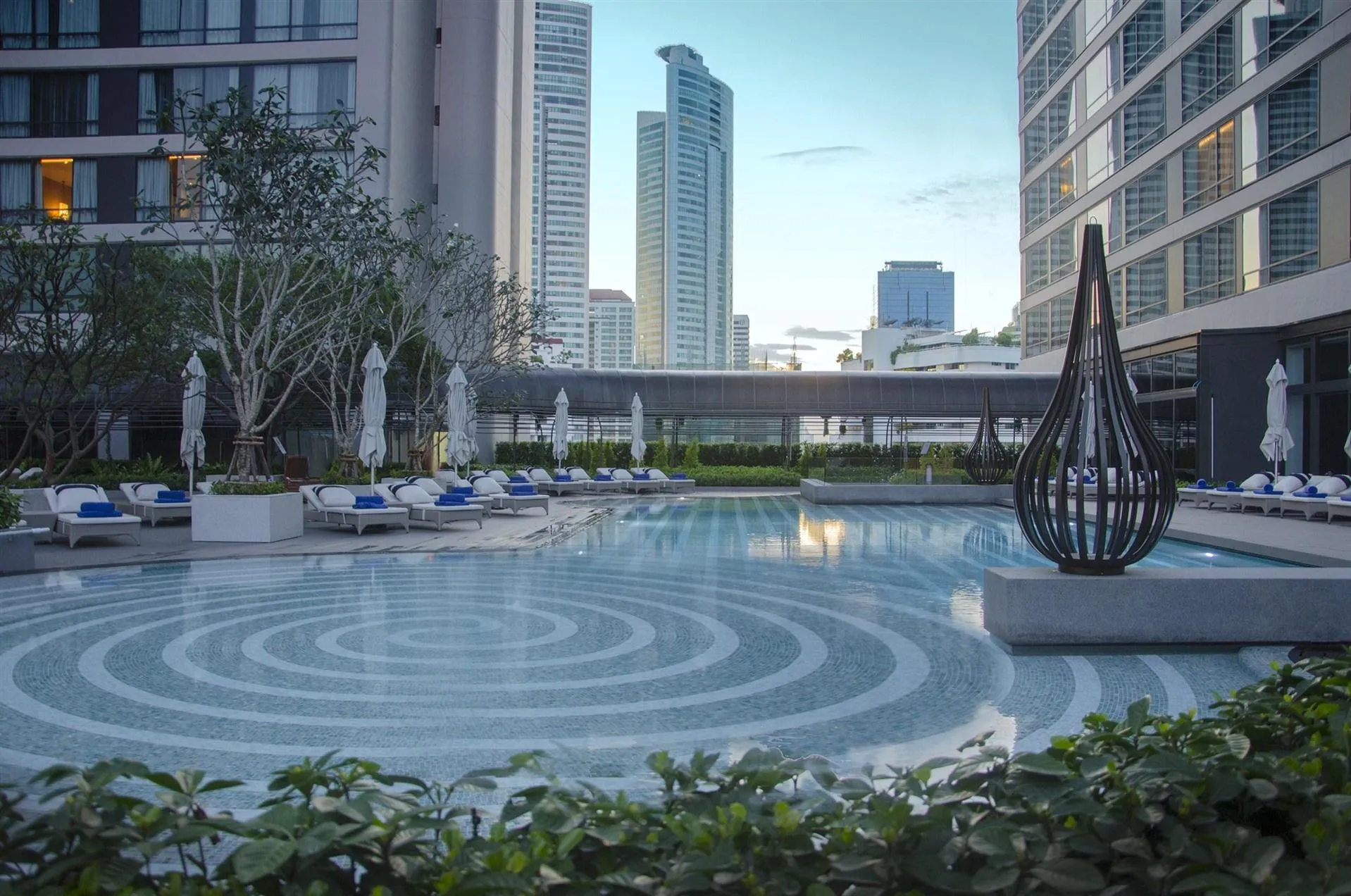 Rooftop swimming pool deck with loungers and the Bangkok city skyline at Bangkok Marriott Marquis Queen's Park