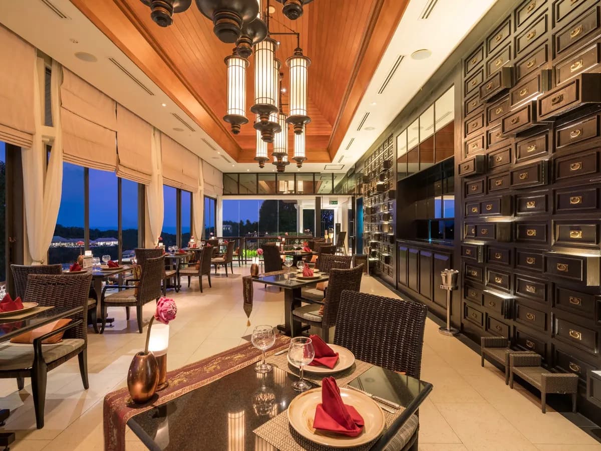 Elegant indoor restaurant with warm lighting and ocean-view windows set for dinner at Banyan Tree Samui