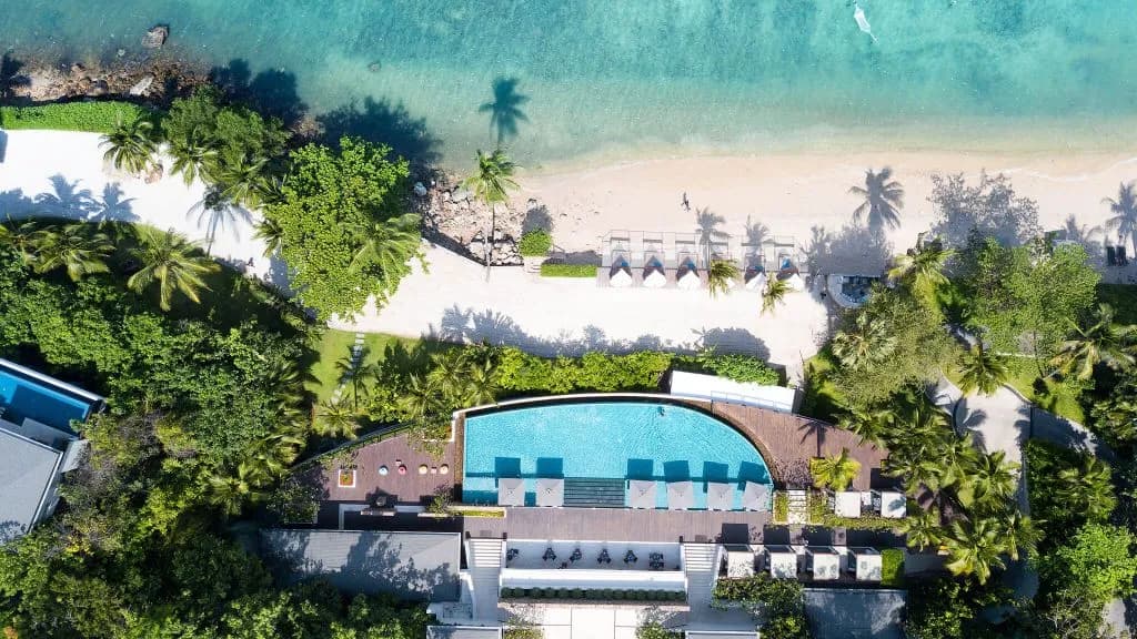 Aerial view of the main infinity pool reaching toward the Gulf of Thailand at Conrad Koh Samui