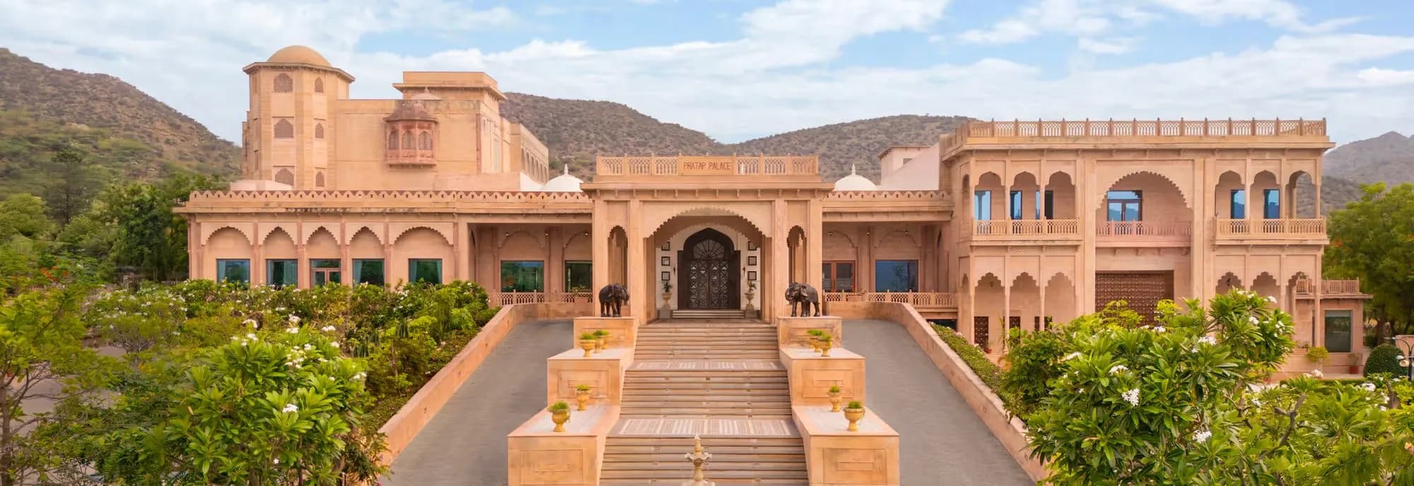 Pratap Mahal Ajmer IHCL SeleQtions honey-toned haveli facade with grand stairway and brass elephants against the Aravalli Hills