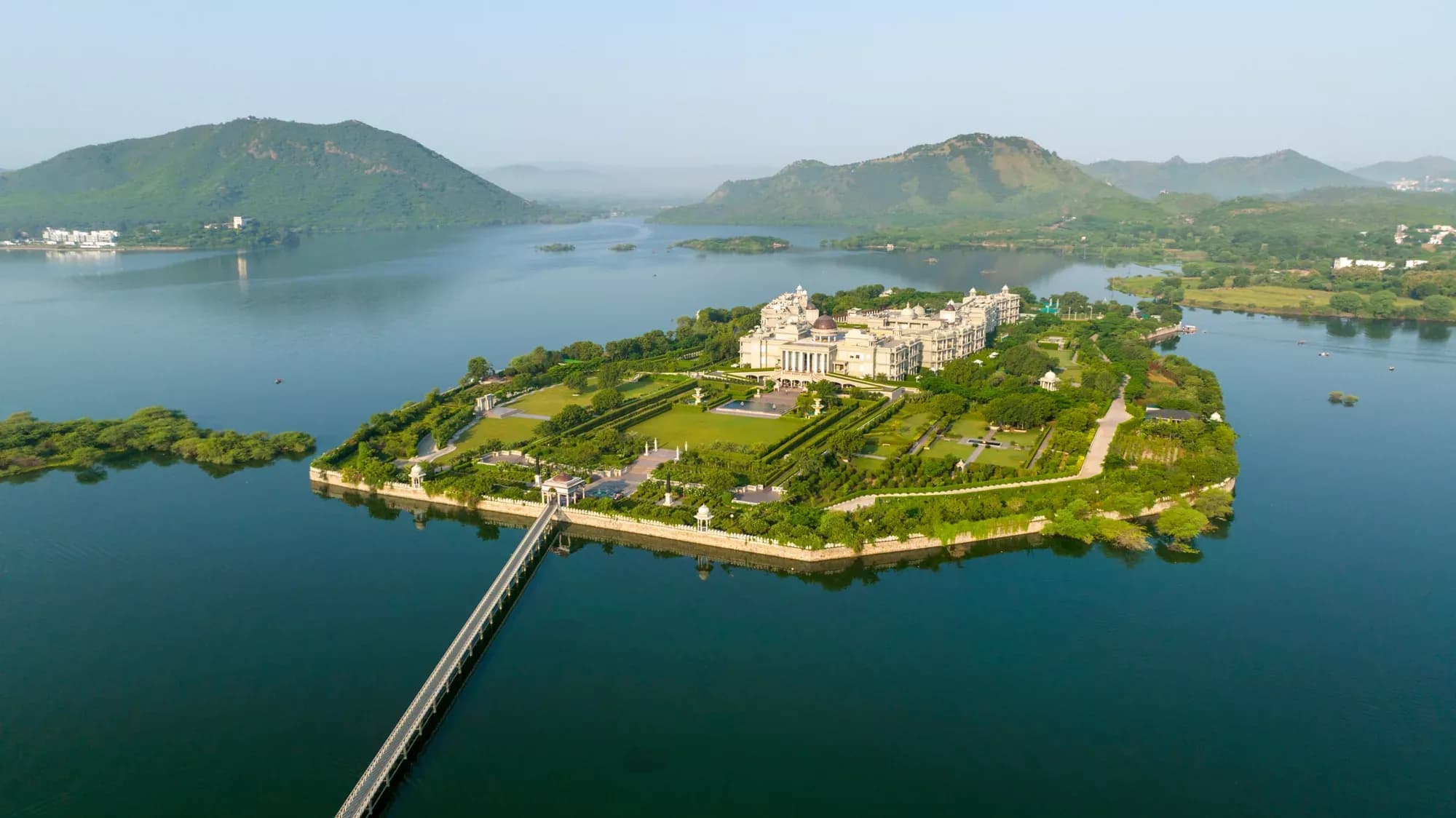 Raffles Udaipur private-island palace resort on Udai Sagar Lake with Aravalli hills beyond