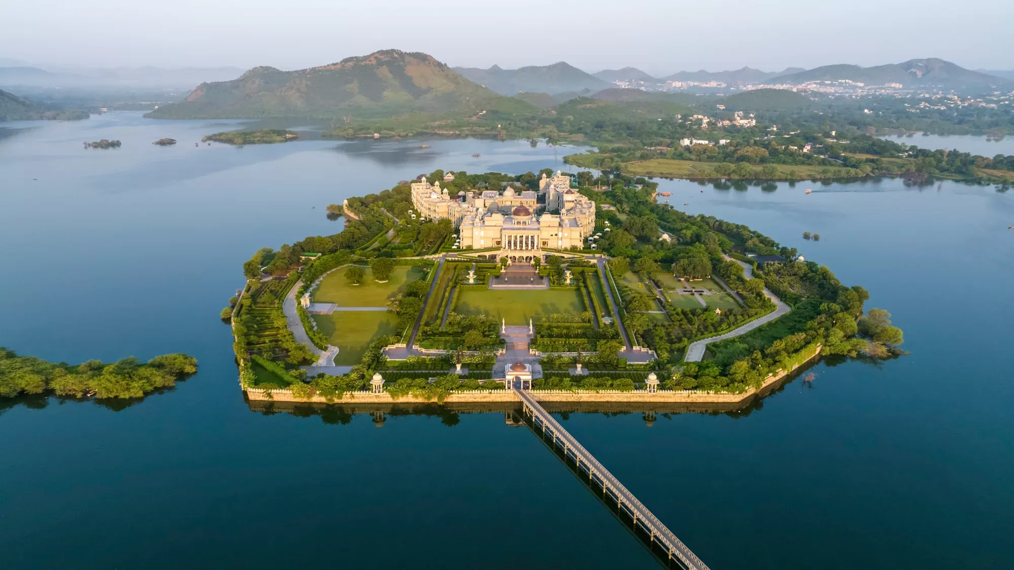 Aerial view of Raffles Udaipur private-island resort on Udai Sagar Lake with Aravalli hills
