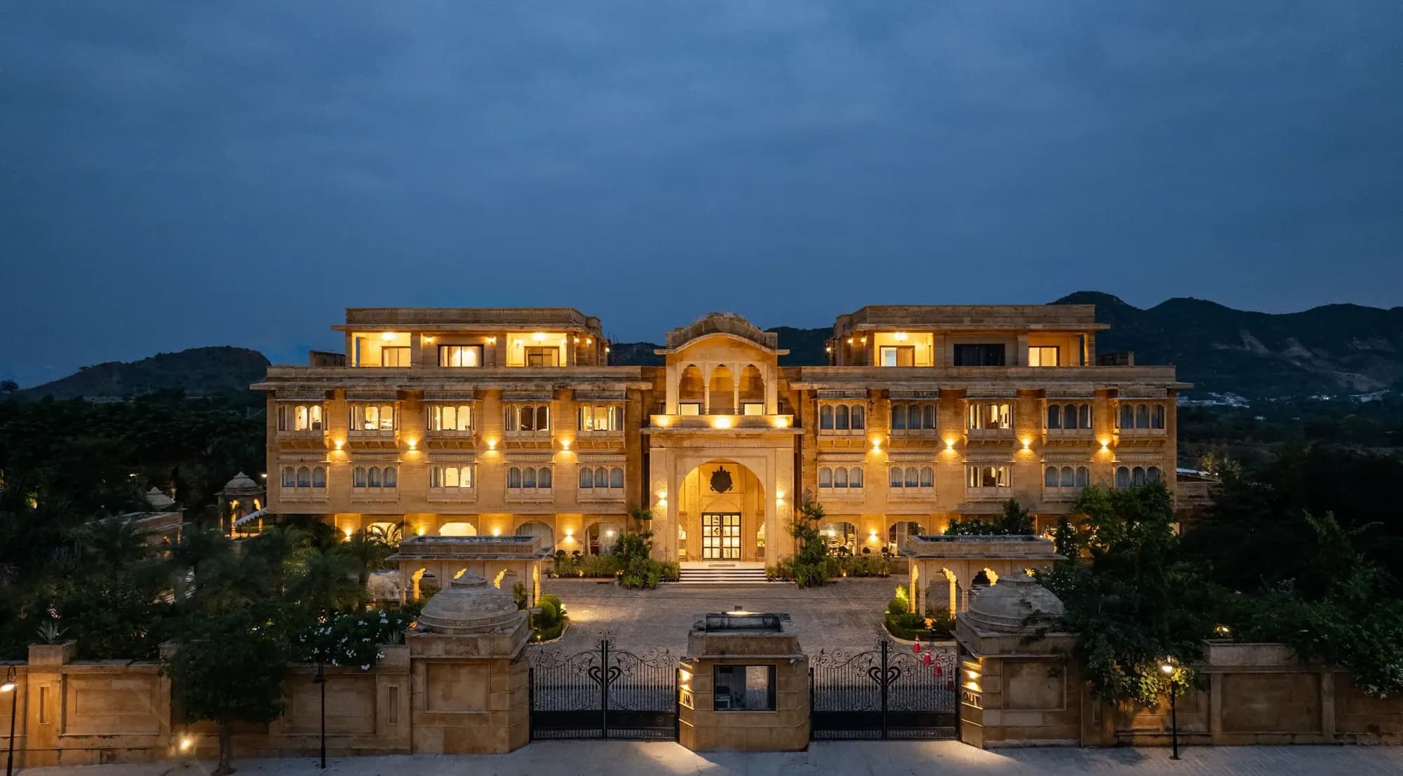 Aerial drone view of Sahdev Bagh Pushkar heritage garden resort with manicured lawns and pool surrounded by the Aravalli foothills