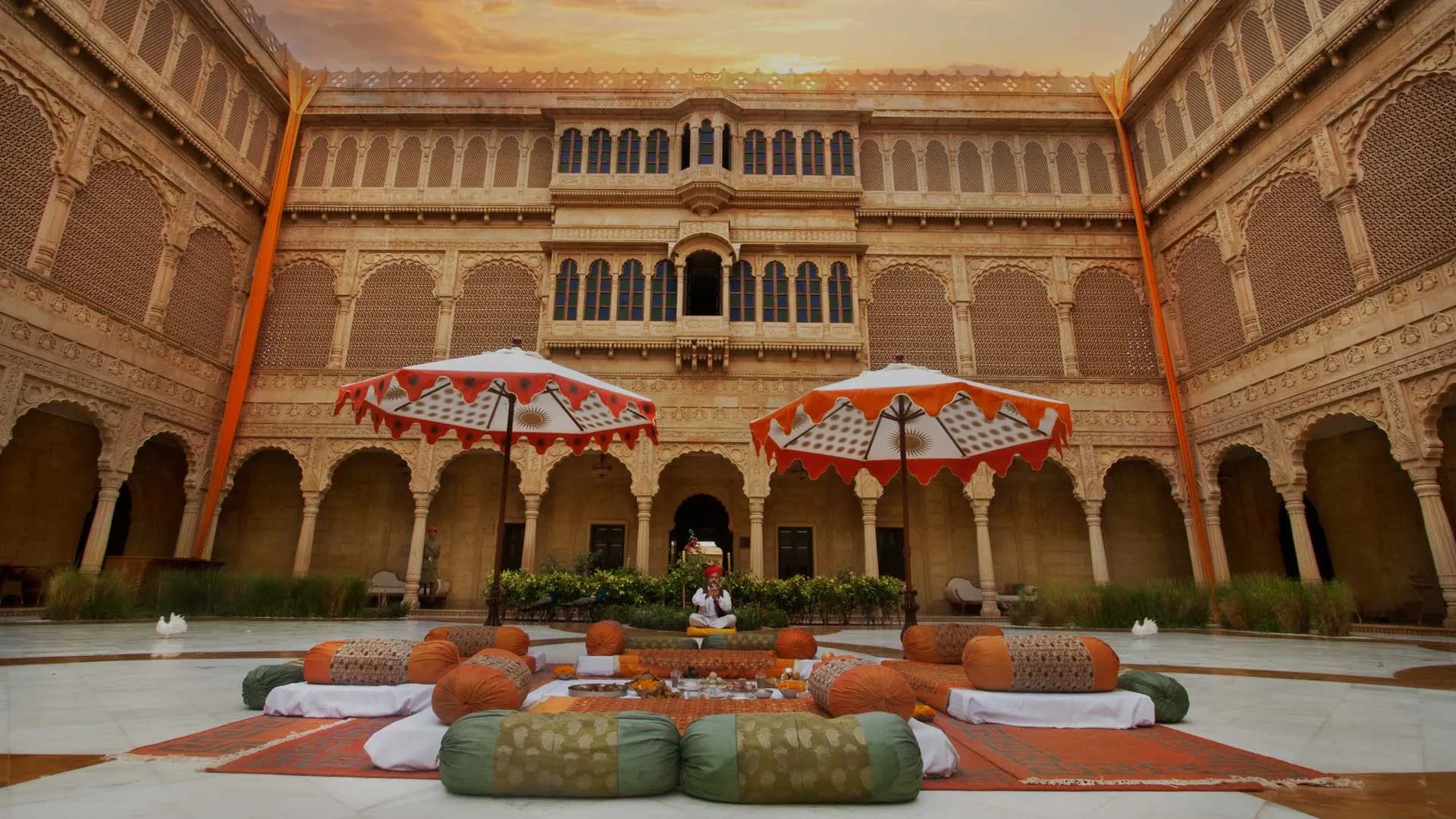 Suryagarh Jaisalmer sandstone fort-hotel facade with carved ramparts and jharokhas glowing gold above the Thar desert