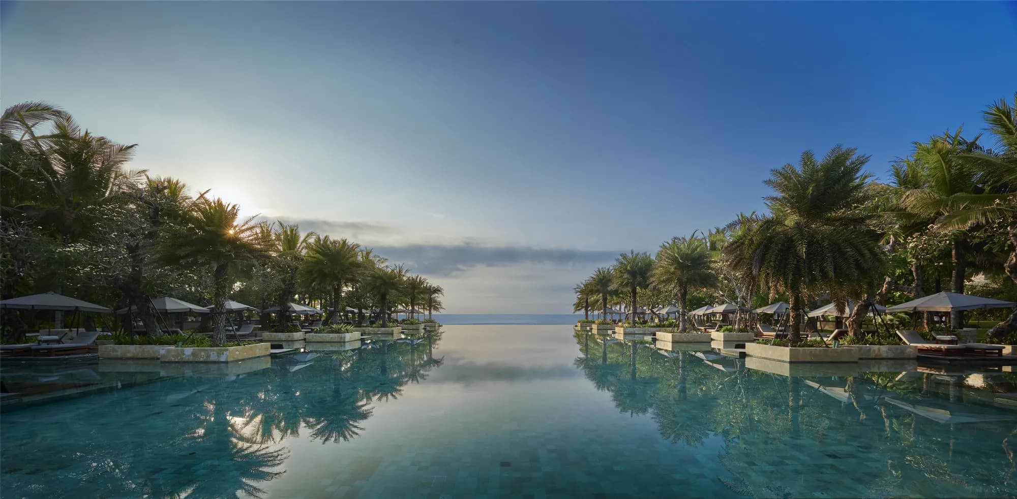 Ocean-front lawn and beach setting with the dramatic resort architecture behind at The Apurva Kempinski Bali, Nusa Dua