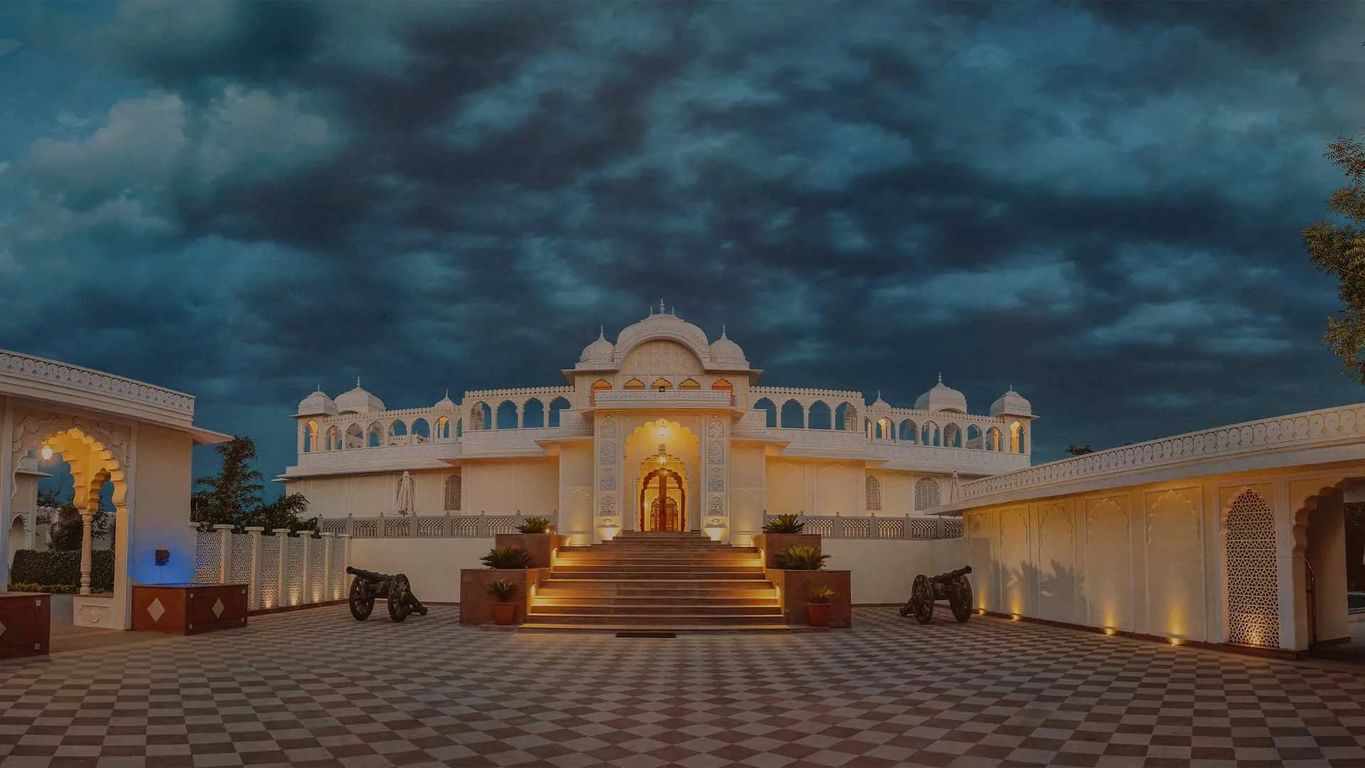 The Tigress Ranthambore heritage-style resort facade with arches and lawns on the edge of Ranthambore National Park