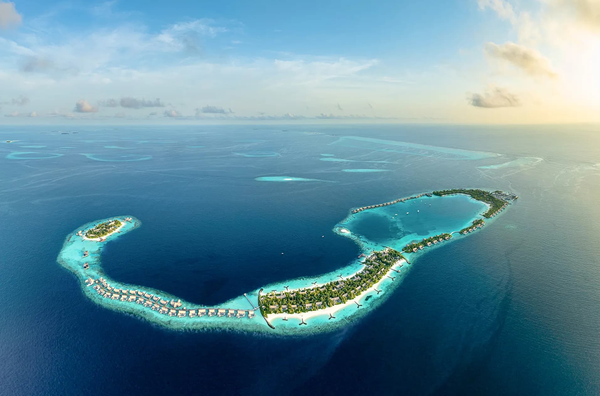 Aerial view of Waldorf Astoria Maldives Ithaafushi three-island resort with overwater villas and turquoise lagoon in the South Malé Atoll