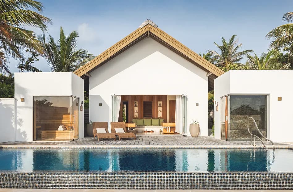 Beach villa exterior with private infinity pool and palms at Waldorf Astoria Maldives Ithaafushi